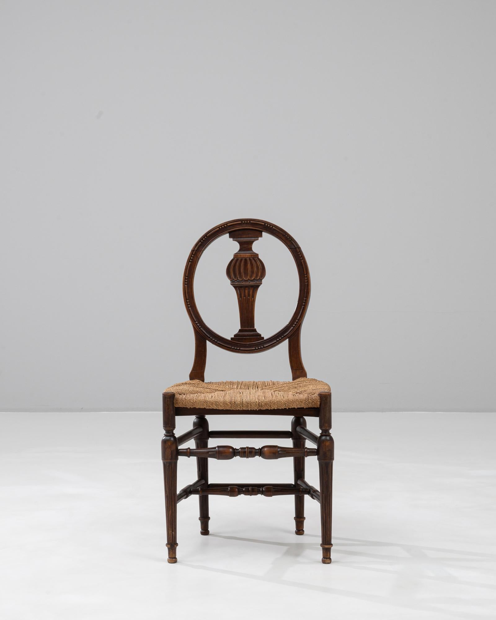 Questa sedia in noce in stile Direttorio francese del XIX secolo mostra la sobria eleganza e le linee pulite neoclassiche caratteristiche del periodo. Lo schienale ovale, centrato da una stecca a forma di balaustro finemente intagliata, offre una