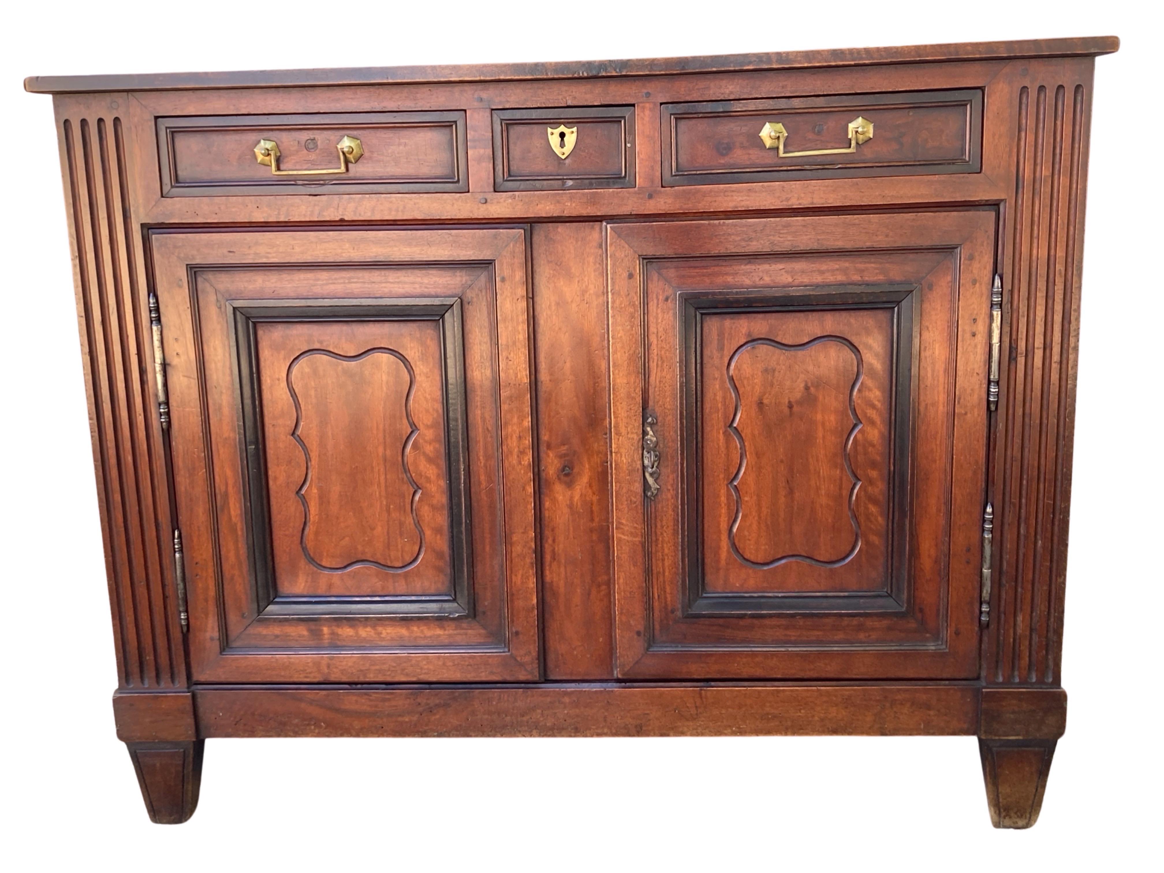 Directoire buffet hand-made in Southern France in the mid 1800s using walnut. The buffet shows a three on two composition with three drawers on top of two doors. The drawers are inset and the fronts are composed of a flat panel framed in darker