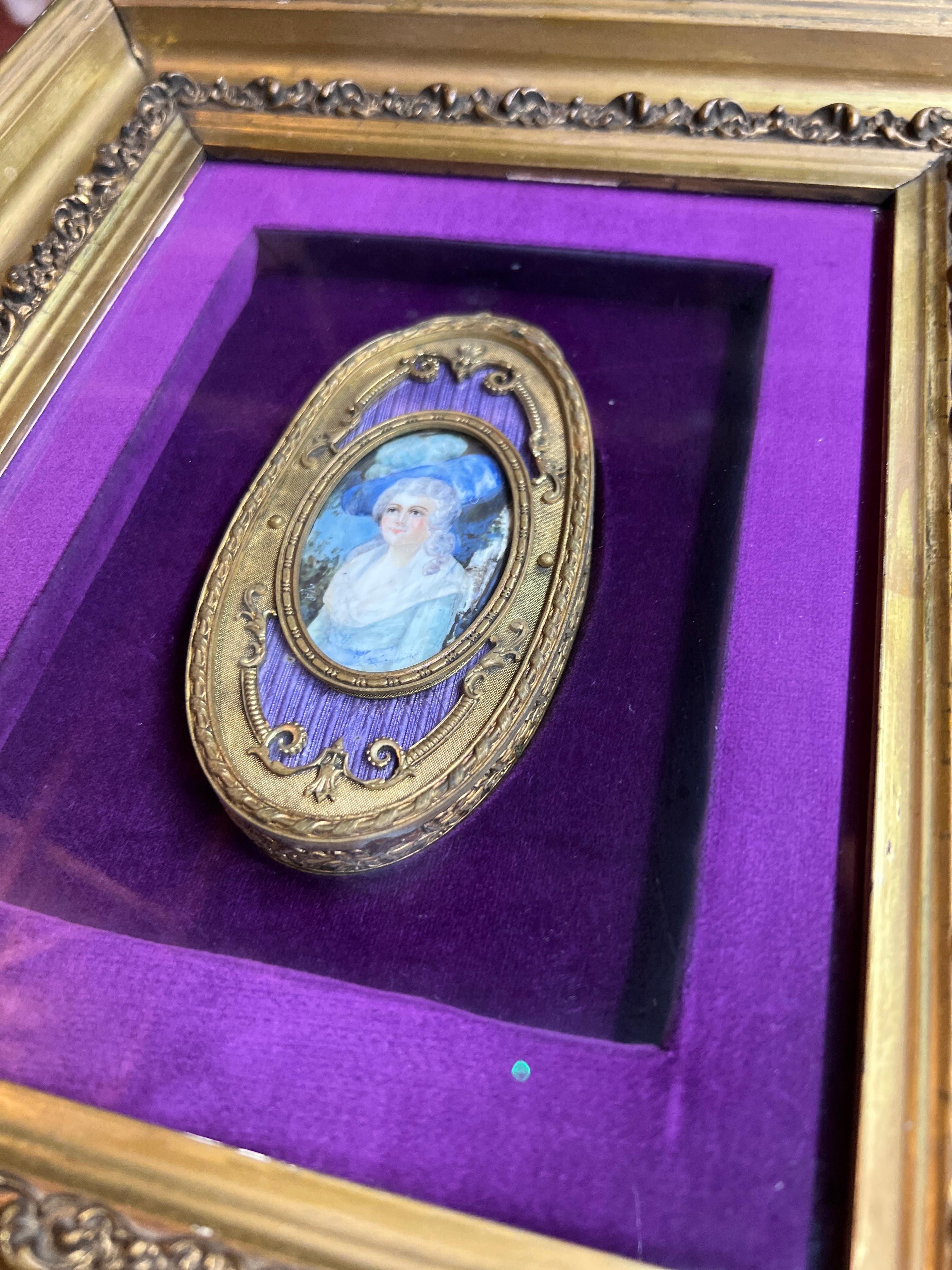 France, circa 1900. 

An antique French school painting of a noble women on likely paper or animal bone. The painting is housed inside a bronze d'ore frame and accented by purple enamel and Neoclassical accents. The entire piece is set on a velvet