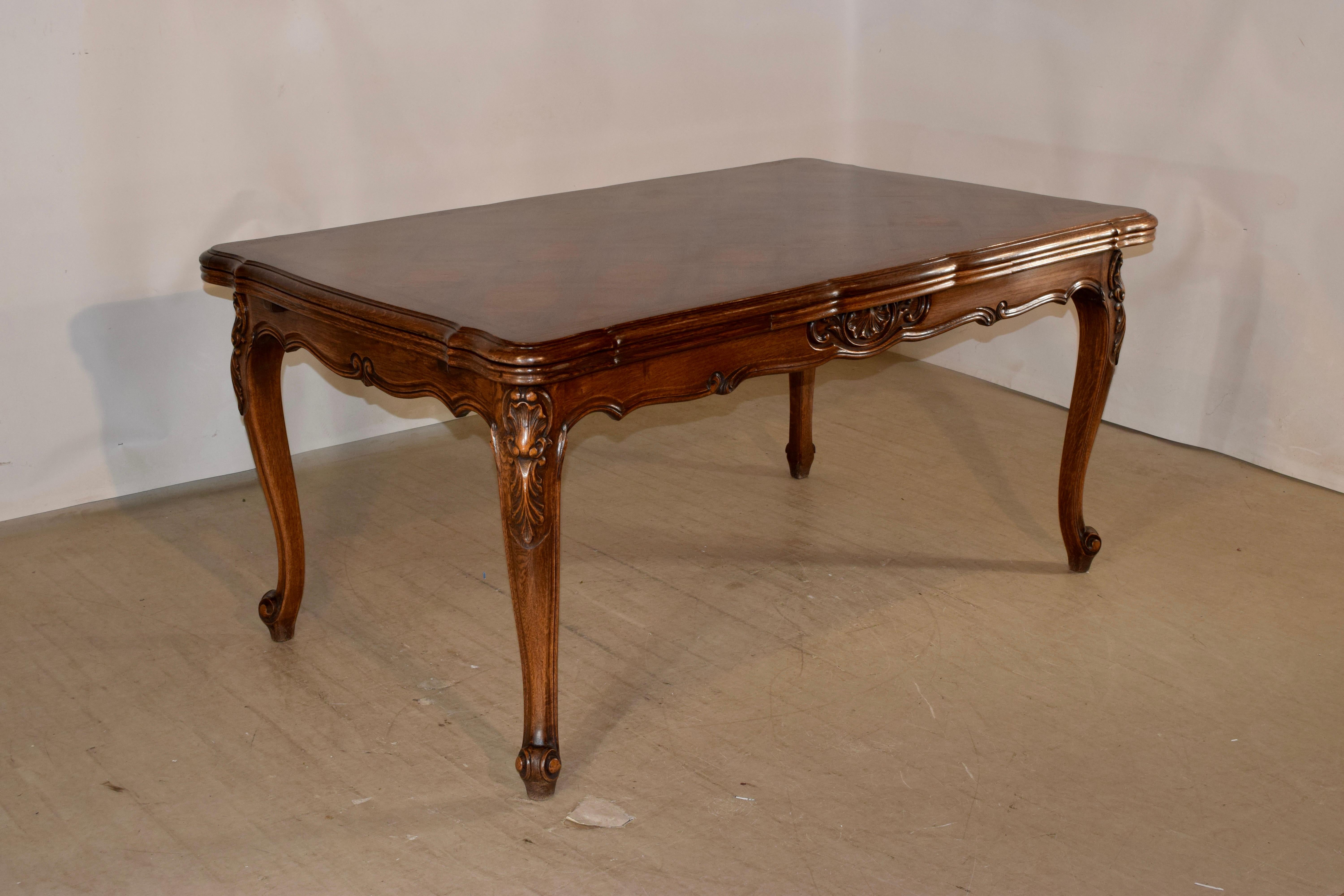 Late 19th century French draw leaf table made from oak with a banded and parqueted top and two extending leaves, following down to a hand scalloped and carved decorated apron and supported on hand carved cabriole legs with carved shell decorations