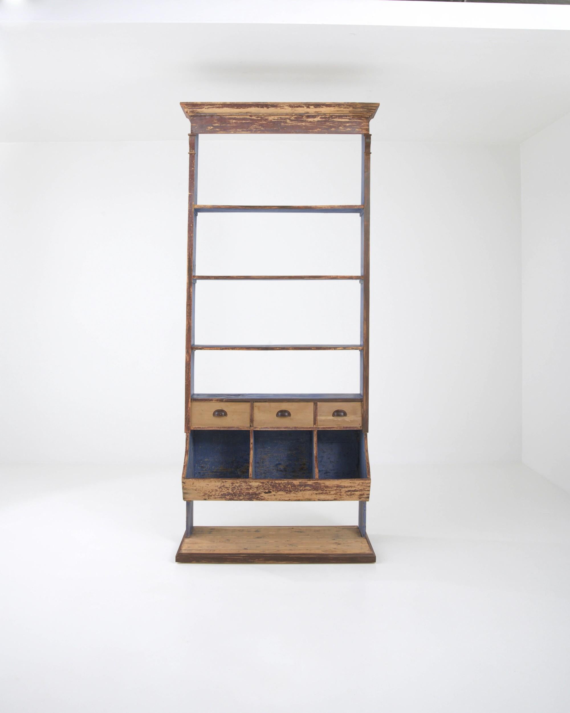 Handcrafted for commercial spaces, this tall wooden shelving unit originates from 19th-century France. Topped by an elegant crown, it features an upper compartment with ample shelves sitting atop a set of deep drawers, with three open sections for