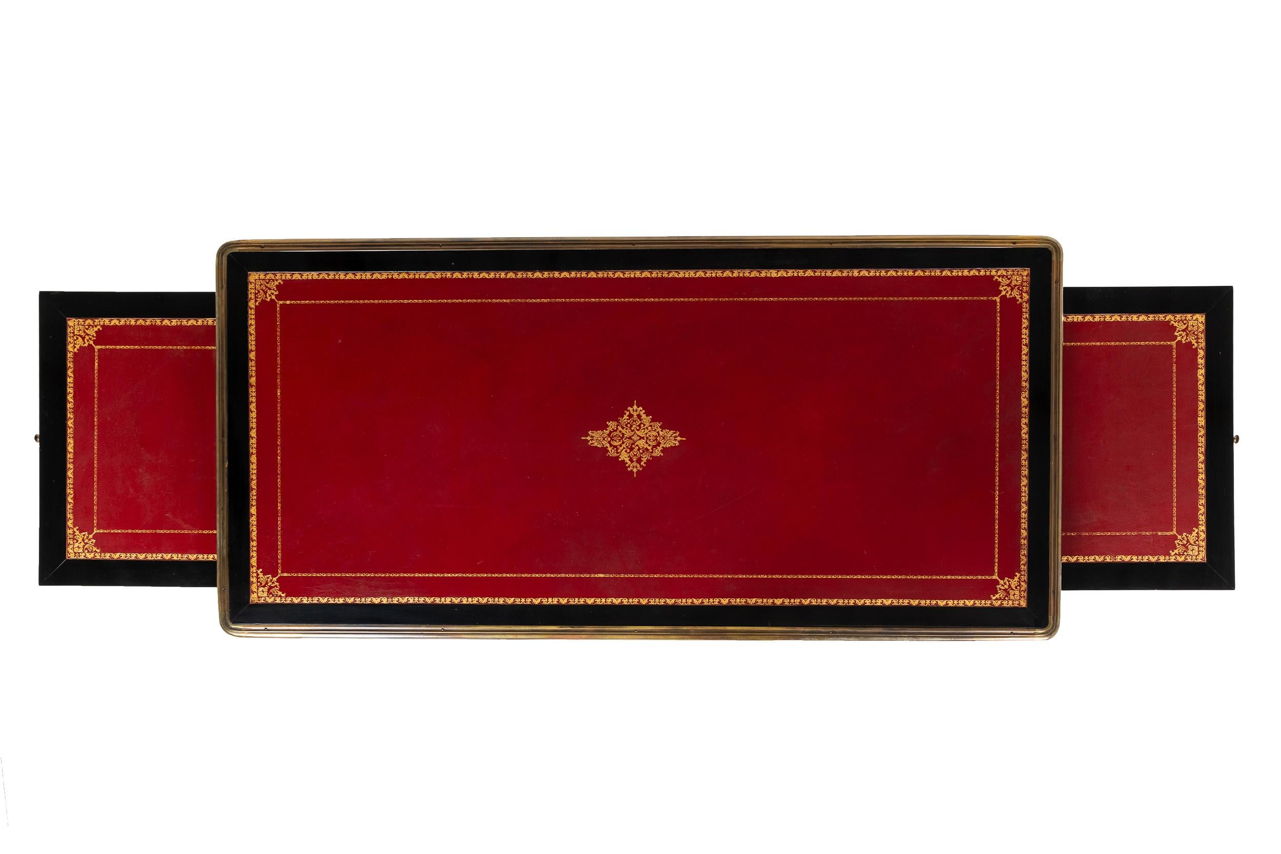 Französisches, ebonisiertes, ausziehbares Bureau plât aus dem 19. Jahrhundert im Louis XV-Stil mit roter Lederplatte. 
Verziert mit Messingfilets, Bronzebeschlägen und vier Bogenfüßen mit vergoldeten Bronzesockeln.
