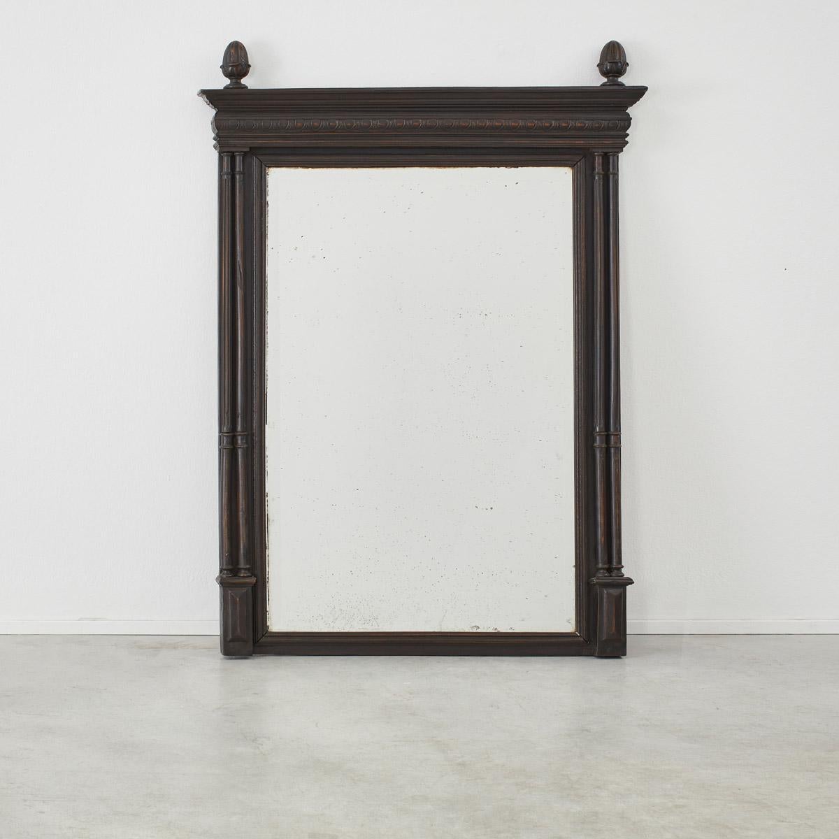 Made in France well over one hundred years ago, this large ebonised mantel mirror is intricately detailed with columns and carved embossments. The mirror’s size and bold character make it well suited to hang above a fireplace or in a hallway. 