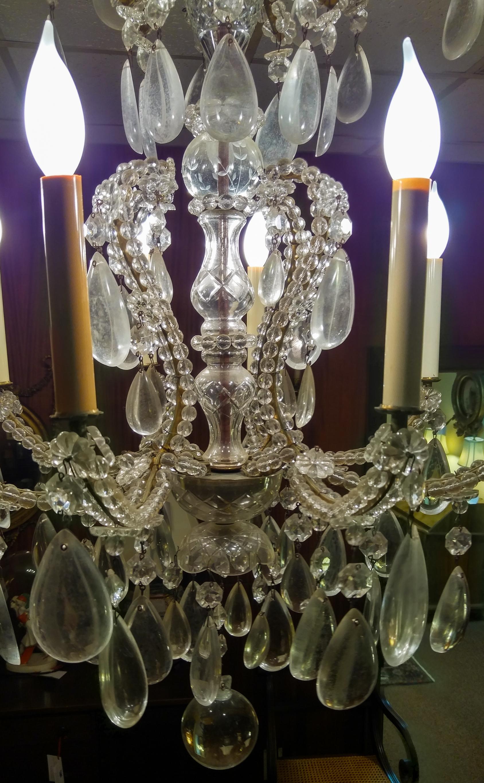 Verschnörkelter französischer Kristalllüster mit einer aufwendigen Vasen-Säule in der Mitte, sehr großen tropfenförmigen Prismen (3,25 Zoll hoch), ausgefallenen Rosetten und einem runden Kristallanhänger. Die acht Arme werden von Glasperlenketten