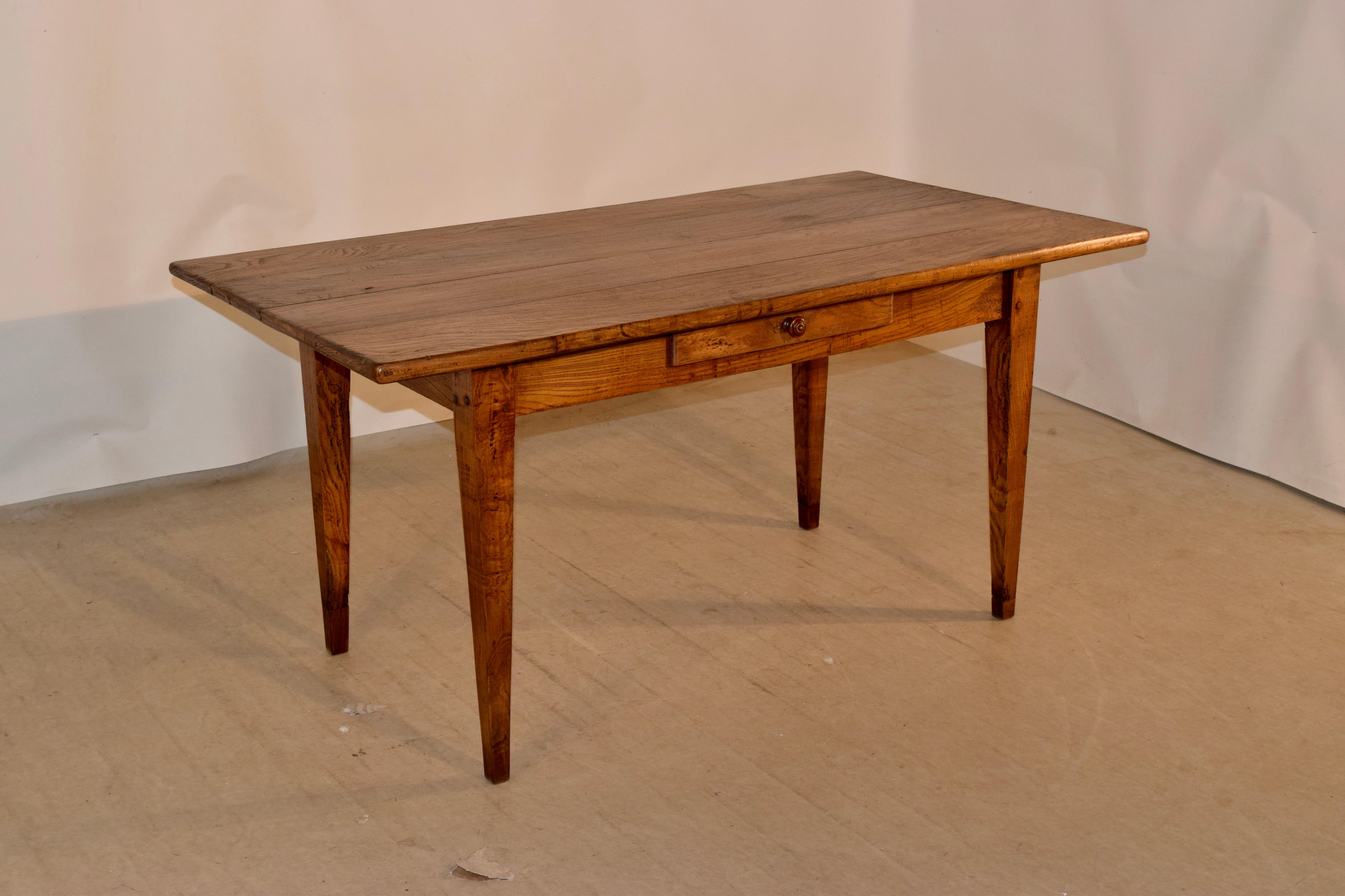 19th century elm farm table from France with wonderfully simple lines. It has a four board top and follows down to a very simple apron containing a single drawer and supported on tapered legs, which have been tipped to add height. The apron measures
