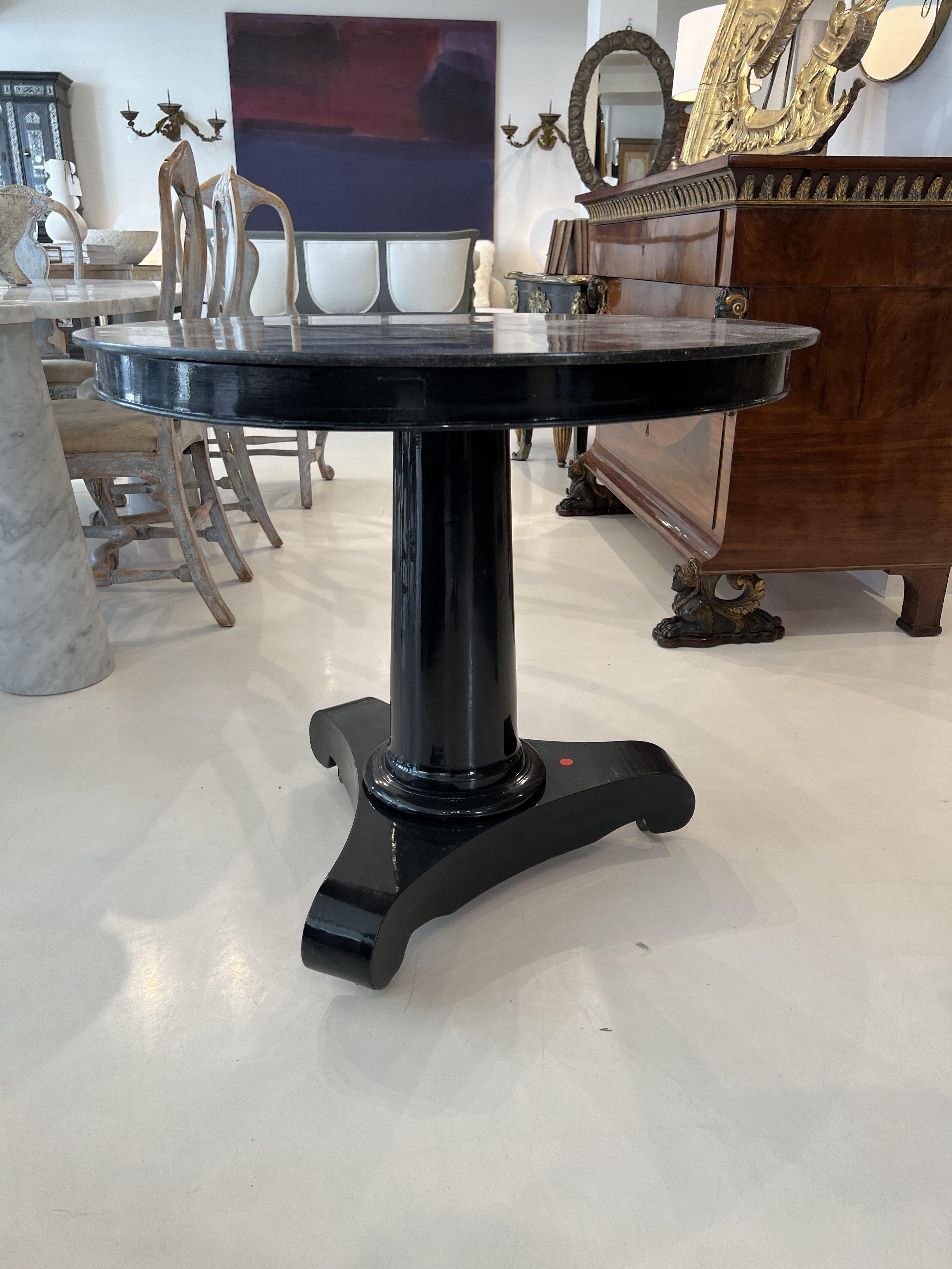 Un distinto guéridon Impero francese del XIX secolo, caratterizzato da un'imponente base laccata nera con raffinati dettagli neoclassici. Il piano rotondo in marmo poggia elegantemente su un semplice piedistallo, mettendo in mostra l'artigianato