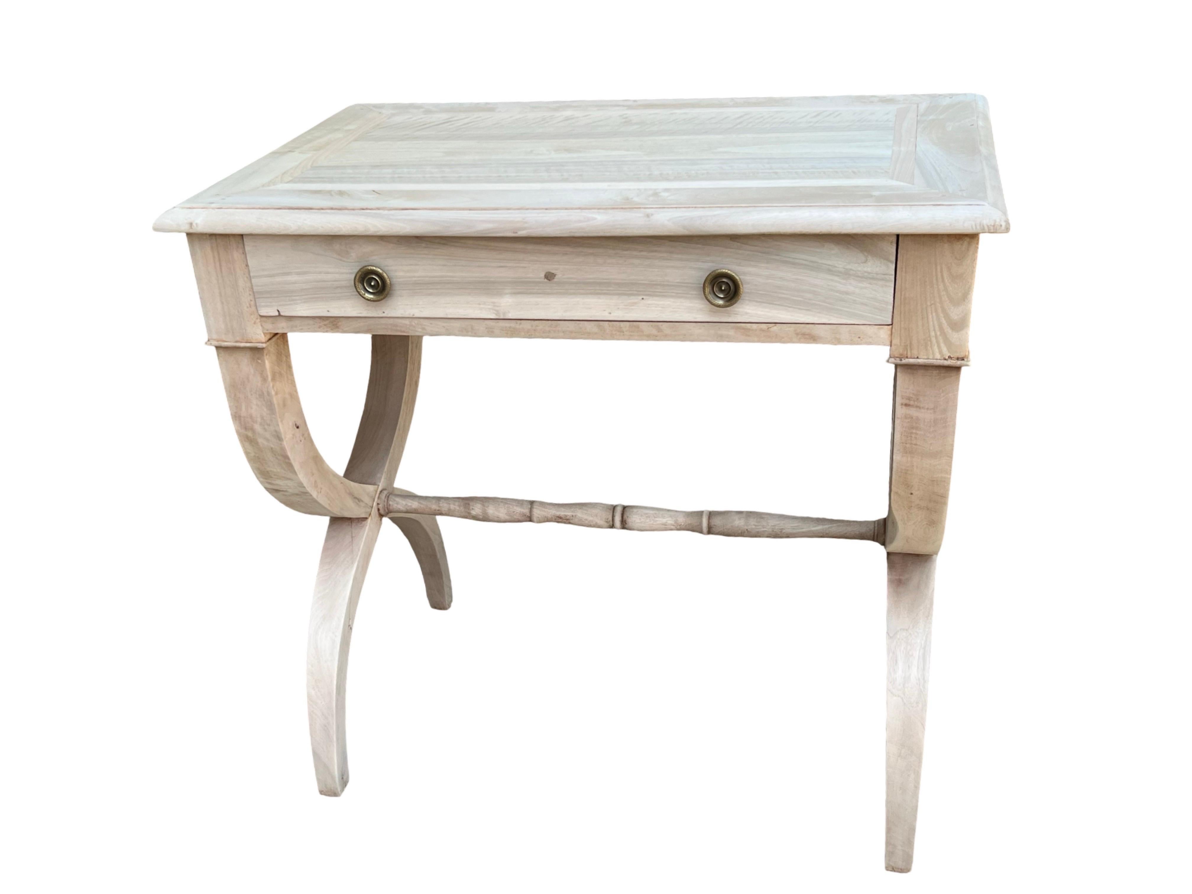 Mesa auxiliar Imperio fabricada a mano en Francia a principios del siglo XIX con madera de cerezo. La mesa es de líneas muy elegantes, con bordes muy rectos que se combinan con patas suaves y curvadas y una cruceta en I torneada a mano. La mesa