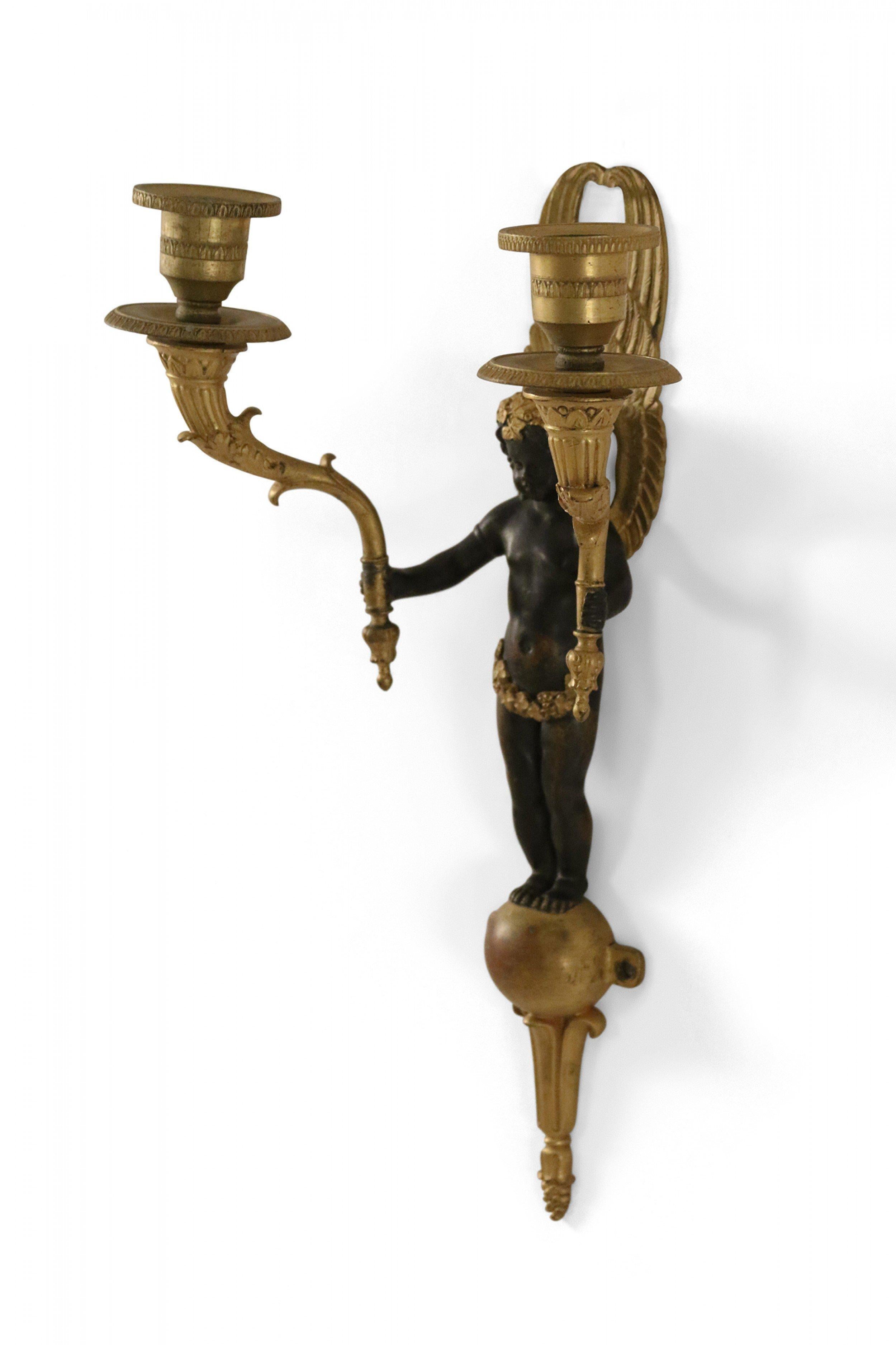French Empire-style (19th century) ebonized bronze and gilt trim caryatid wall sconce with a central winged figure holding two candleholders.
 