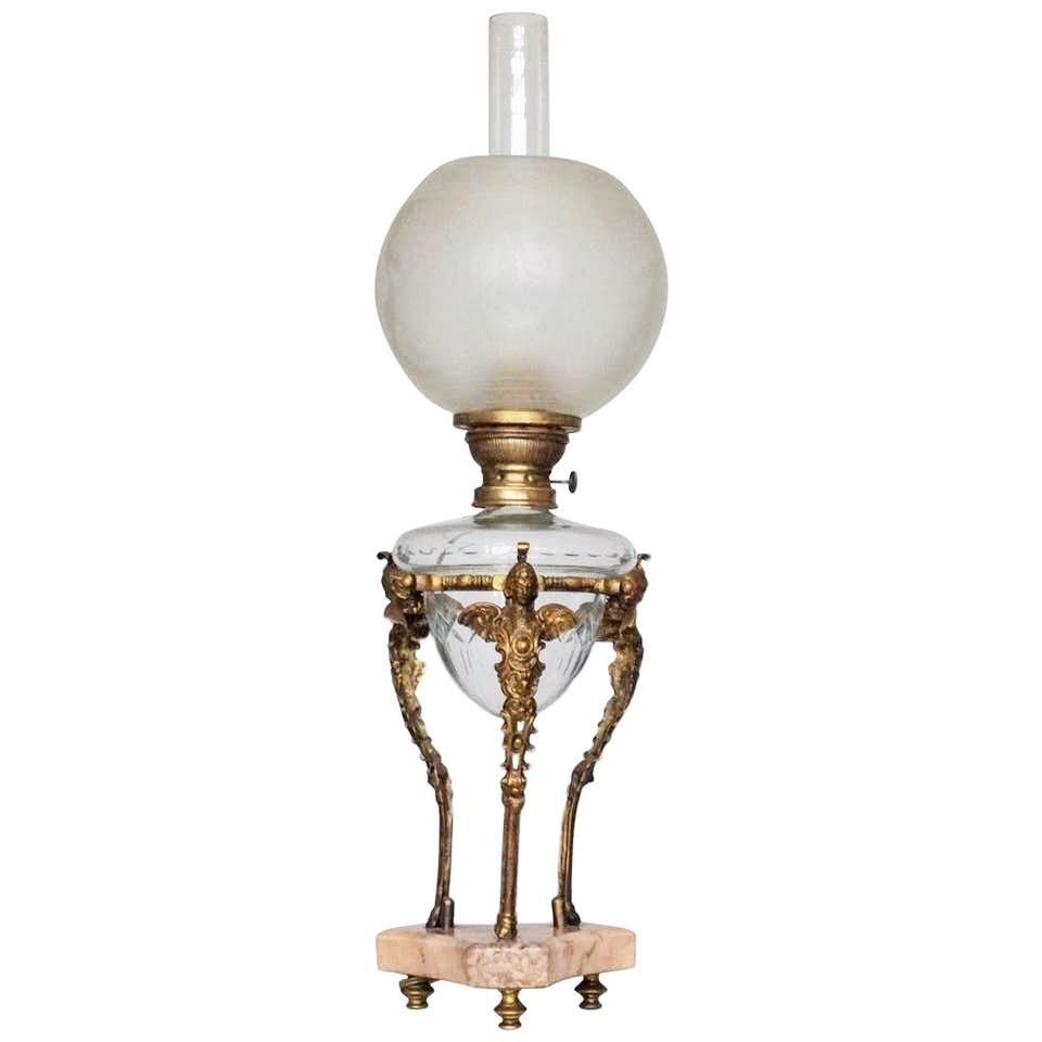 Empire style oil lamp converted to electric with cut crystal oil reservoir encircled by gilt bronze trefoil satyrs raised on a rose marble trefoil plinth. Original etched glass globe with beautiful Empire motifs, hurricane glass chimney, France,