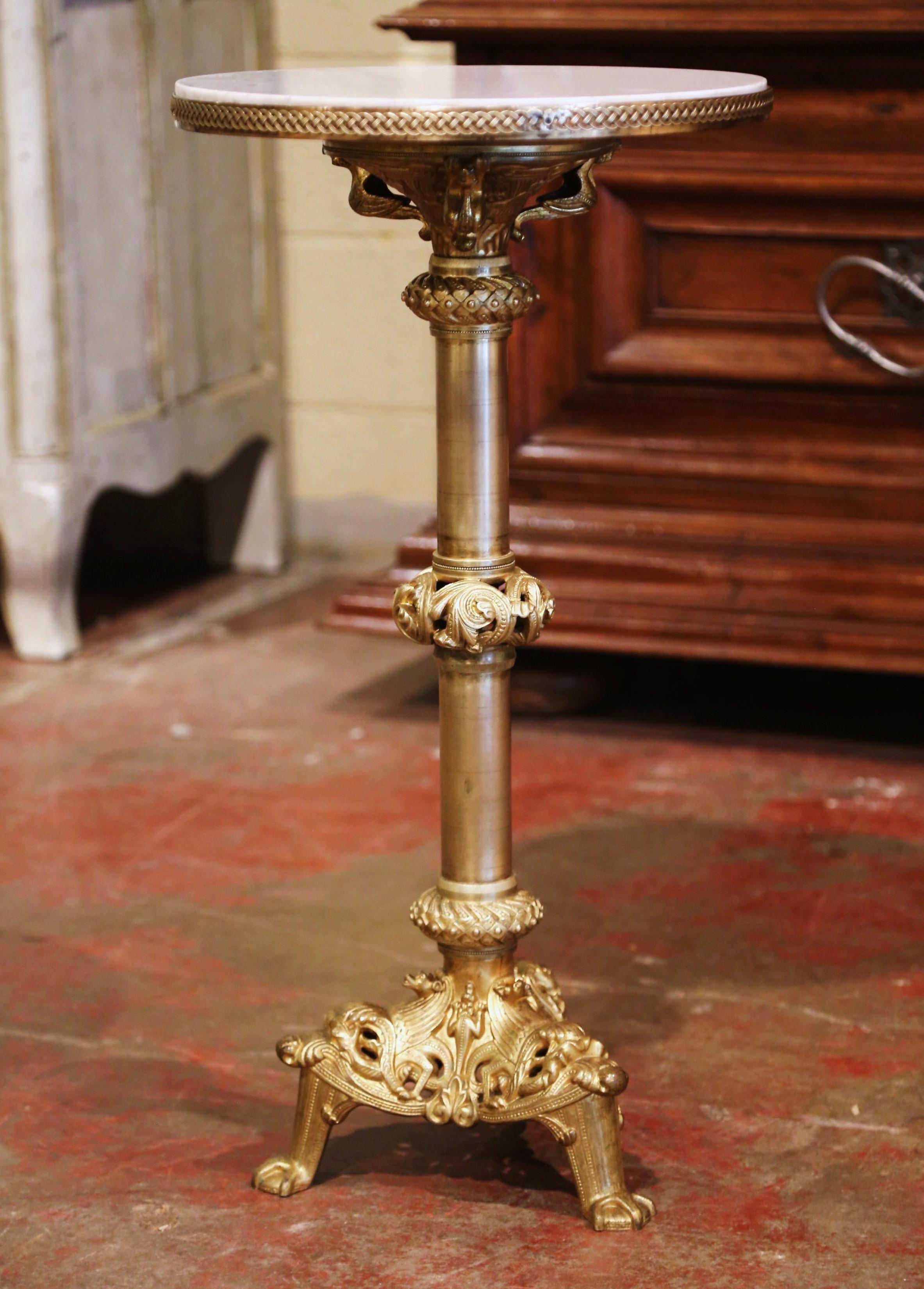 This elegant antique bronze and marble table was created in Paris, France, circa 1880. The pedestal stands on an intricate base ending with three carved paw feet. The round stem is decorated with leaf and foliage motifs over a circular white marble