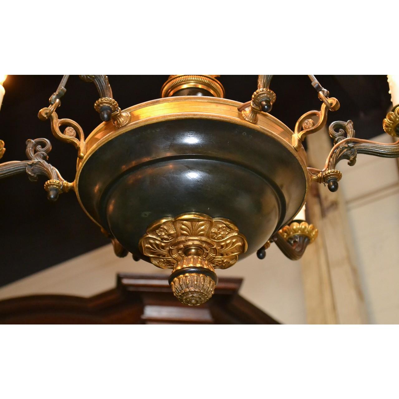 Impressive 19th century French Empire style bronze and tole chandelier. The bowl-shaped base surmounted by six scrolling horn-shaped arms with flower-petal candle cups, and centered by a beautiful flower and flame finial. The bottom with an