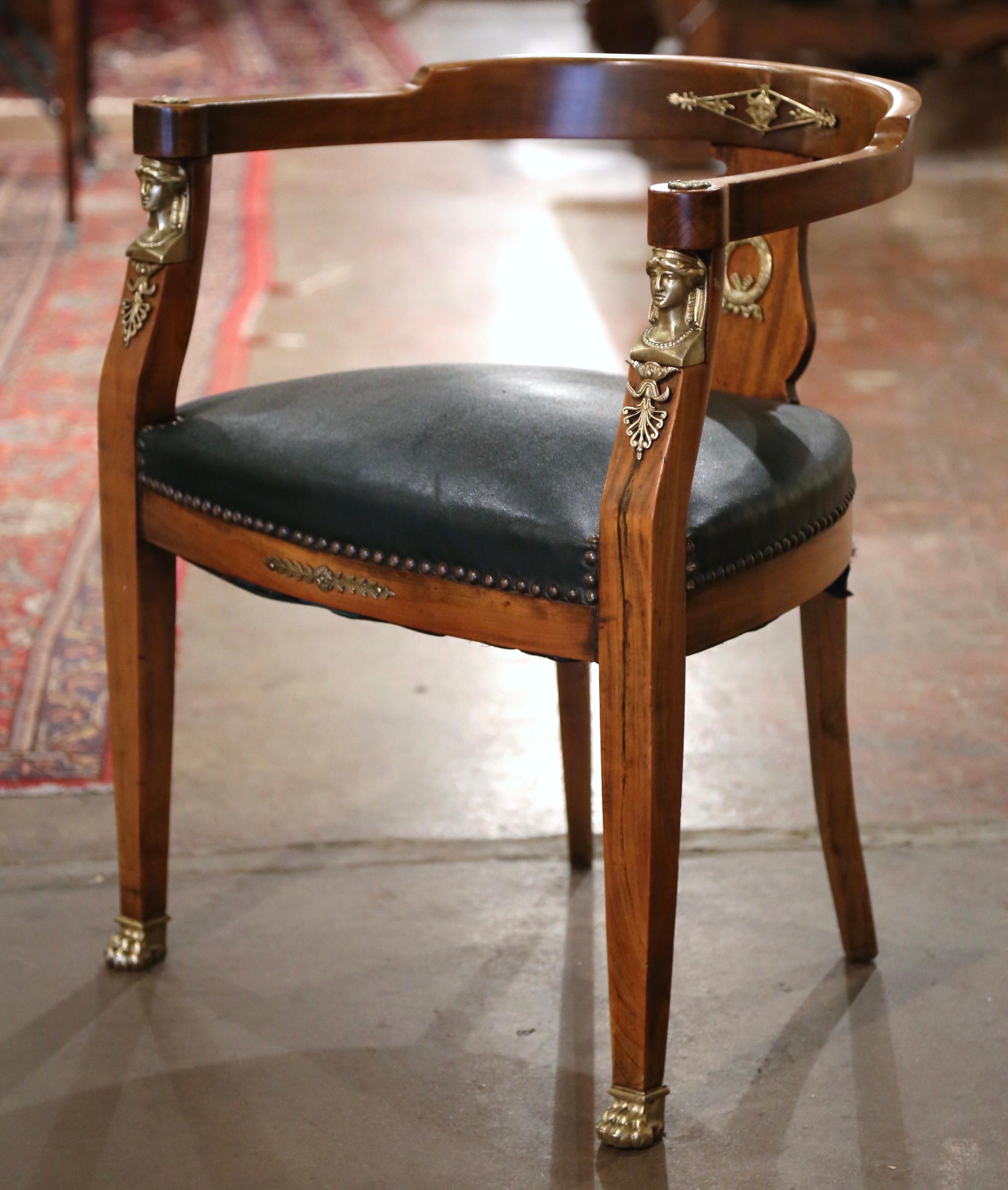 Decorate a man's office or study with this elegant antique armchair. Hand carved in France circa 1870 and built of cherry, the armchair stands on tapered front legs ending with paw sabot feet, over a bombe apron decorated with a brass laurel leaf