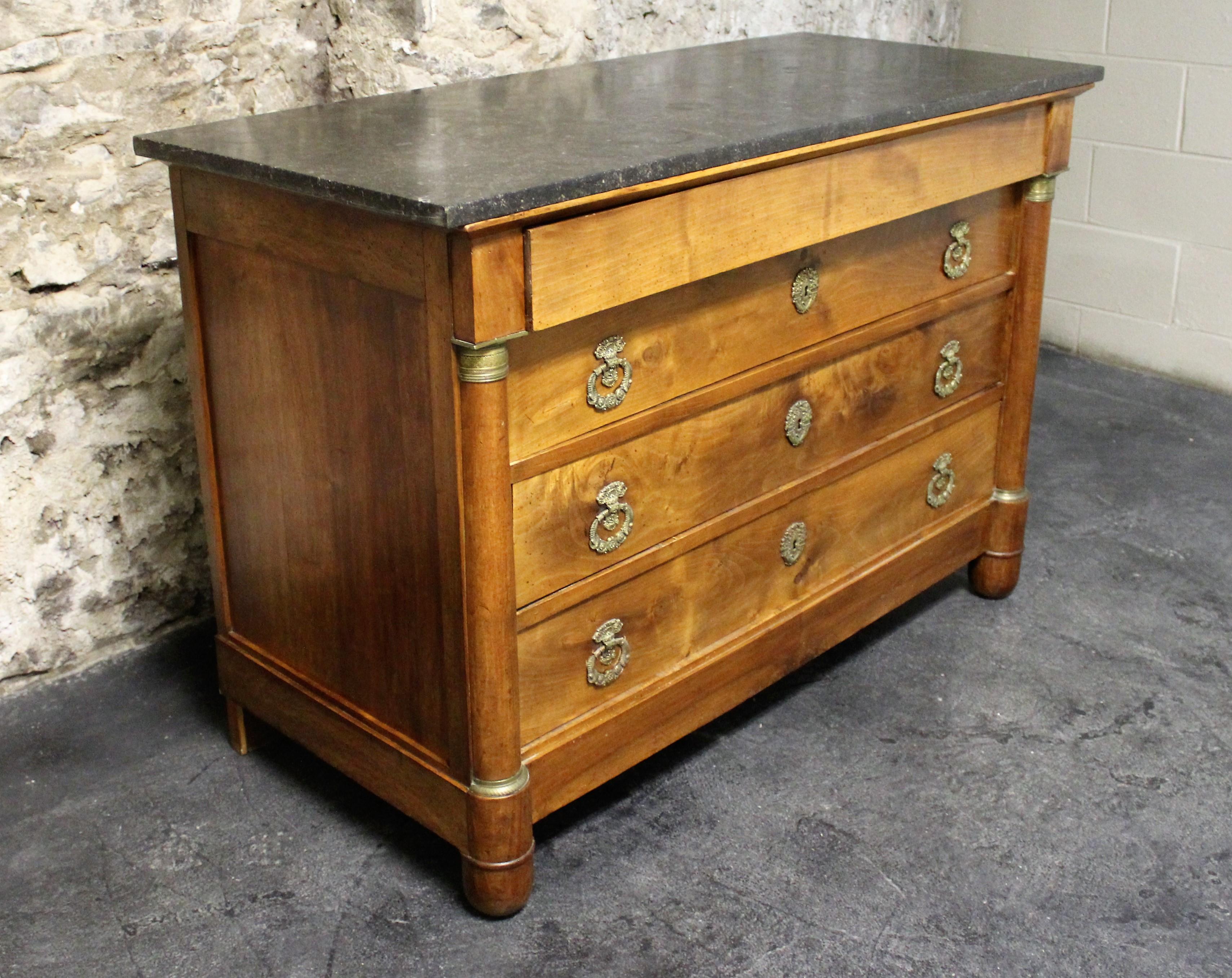19th century French Empire three plus one drawer walnut commode featuring bronze accents, hardware and a black marble-top.