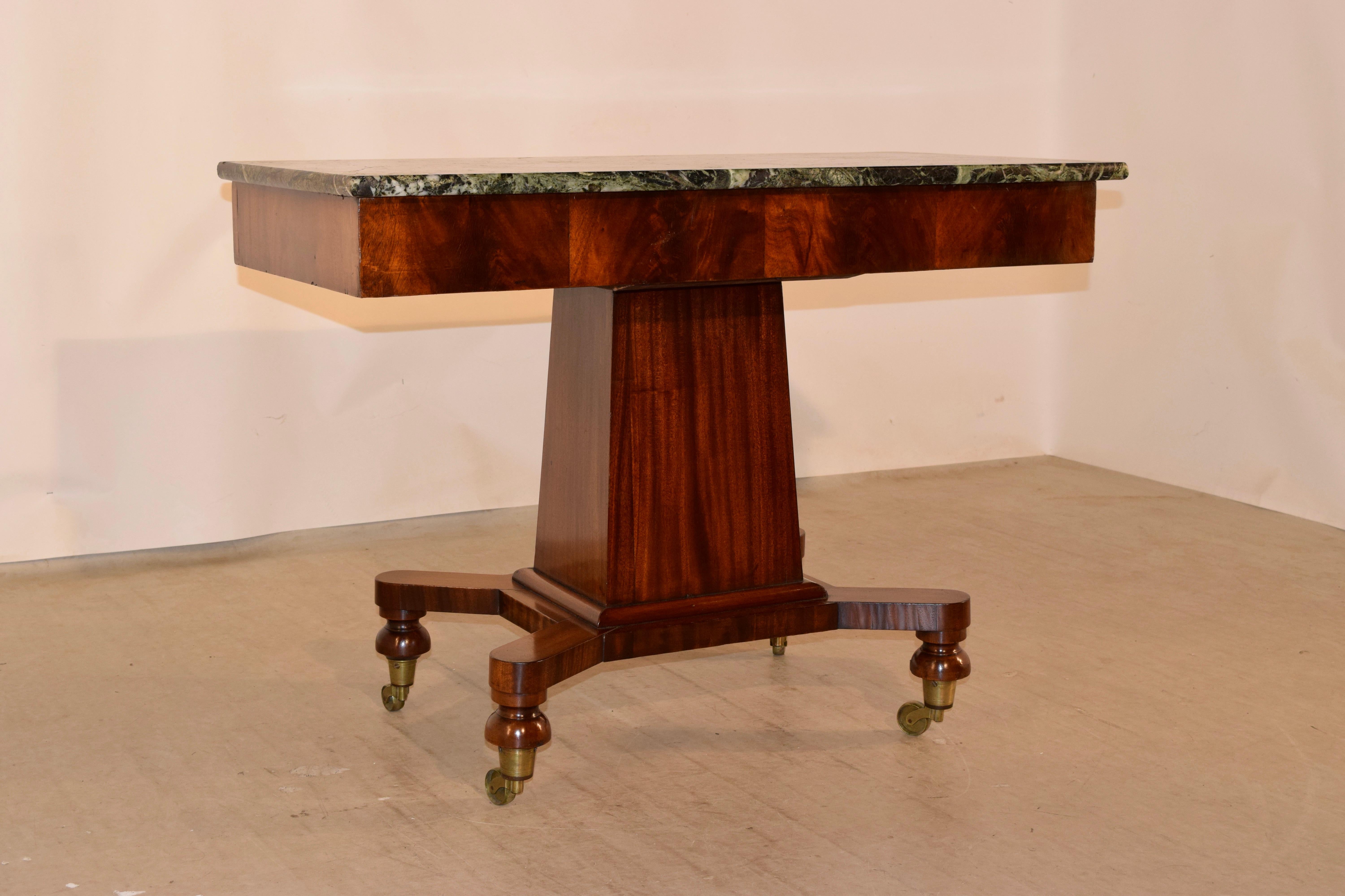 19th century French Empire console table with a marble top supported on a tapered pedestal base made from mahogany with gorgeous graining. The central pedestal is supported on four legs which retain their original casters. The table is simple and