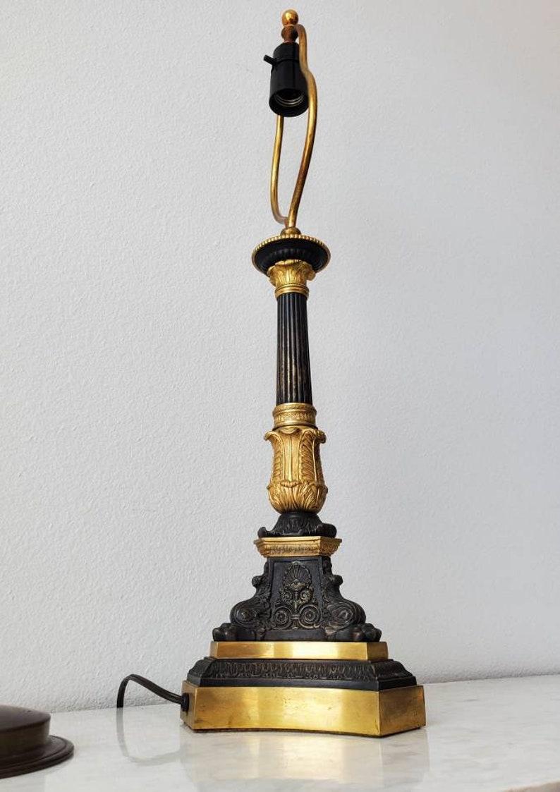 A fine Parisian Napoleon III Second Empire antique well cast dore bronze candlestick, electrified and converted to a table lamp. Having a heavy tripartite base with clawed foot atop shaped plinth, single rich detail and carved acanthus leaf