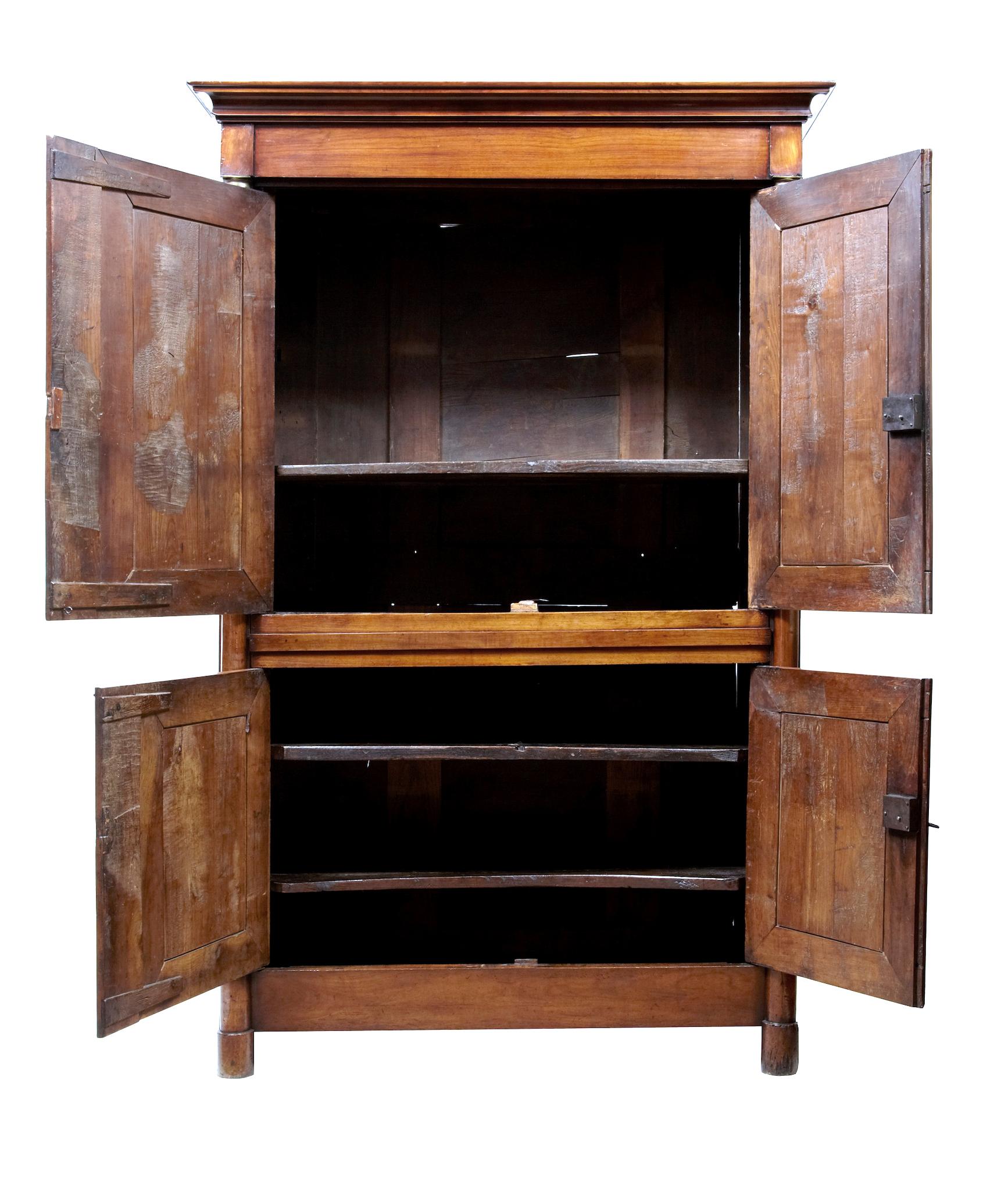 19th century French empire fruitwood armoire cupboard circa 1810.

Made in 1 piece and of grand proportions. Shaped cornice with 2 double door cupboards below. Upper cupboard opens to a single shelf and area that lends its self perfectly to