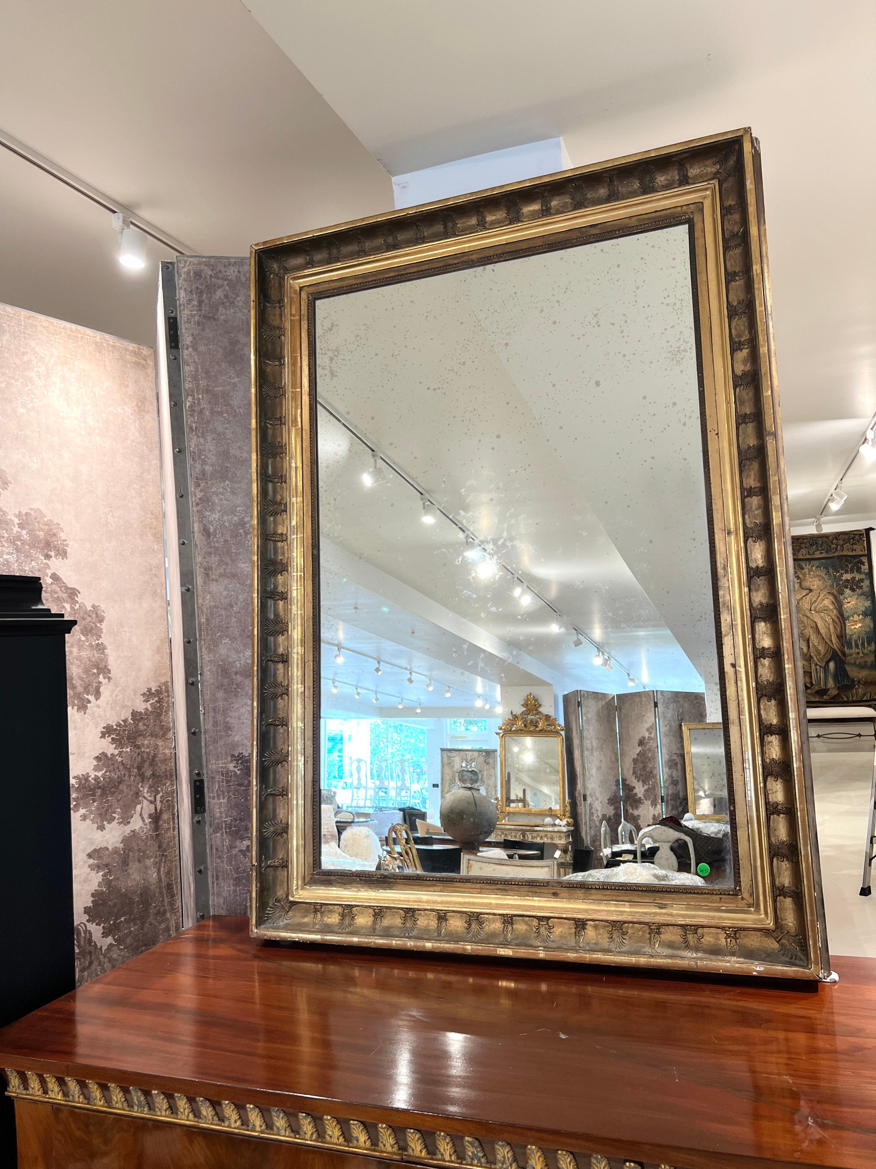 Un majestueux miroir Empire français du XIXe siècle avec un cadre richement doré, présentant des motifs et des détails classiques - reflétant la grandeur et le symbolisme impérial du design napoléonien.