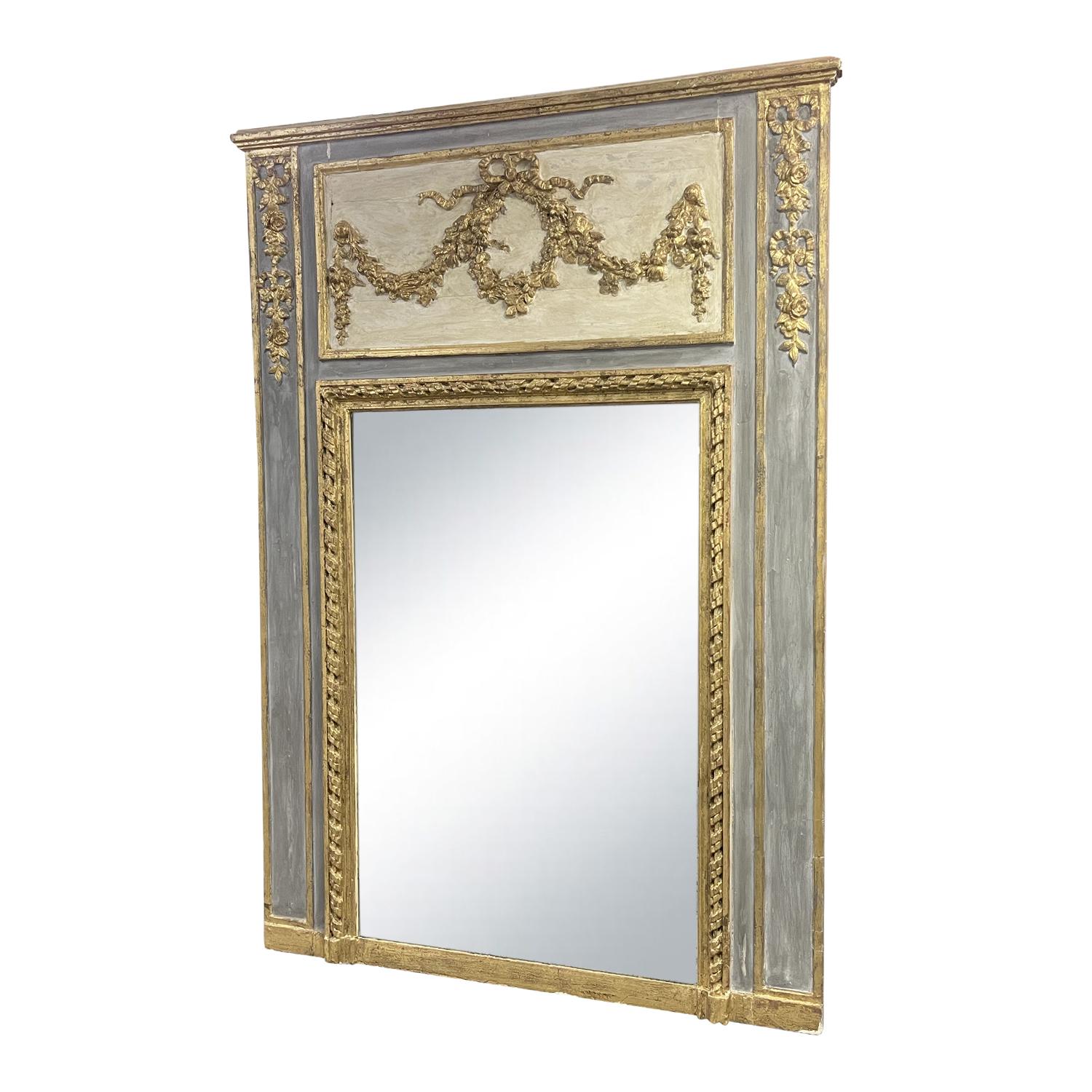 Miroir ancien français du XIXe siècle, patiné en gris-bleu. Bois partiellement doré et verre miroir d'origine, en bon état. Le haut du cadre du miroir trumeau Louis XVI est richement décoré et doré avec des guirlandes, des motifs floraux et des