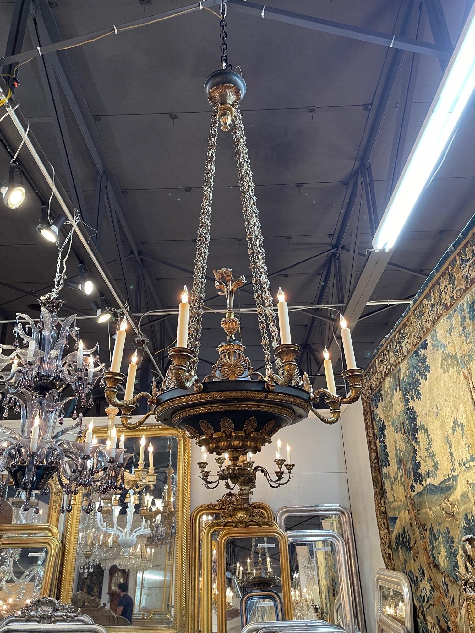 Handsome 19th century French Empire gilt bronze and tole chandelier with 8 lights. Such beautiful decorative tole details on this piece with leaf like and floral images and gorgeous arms as well. The chain is also extra special. Fabulous!