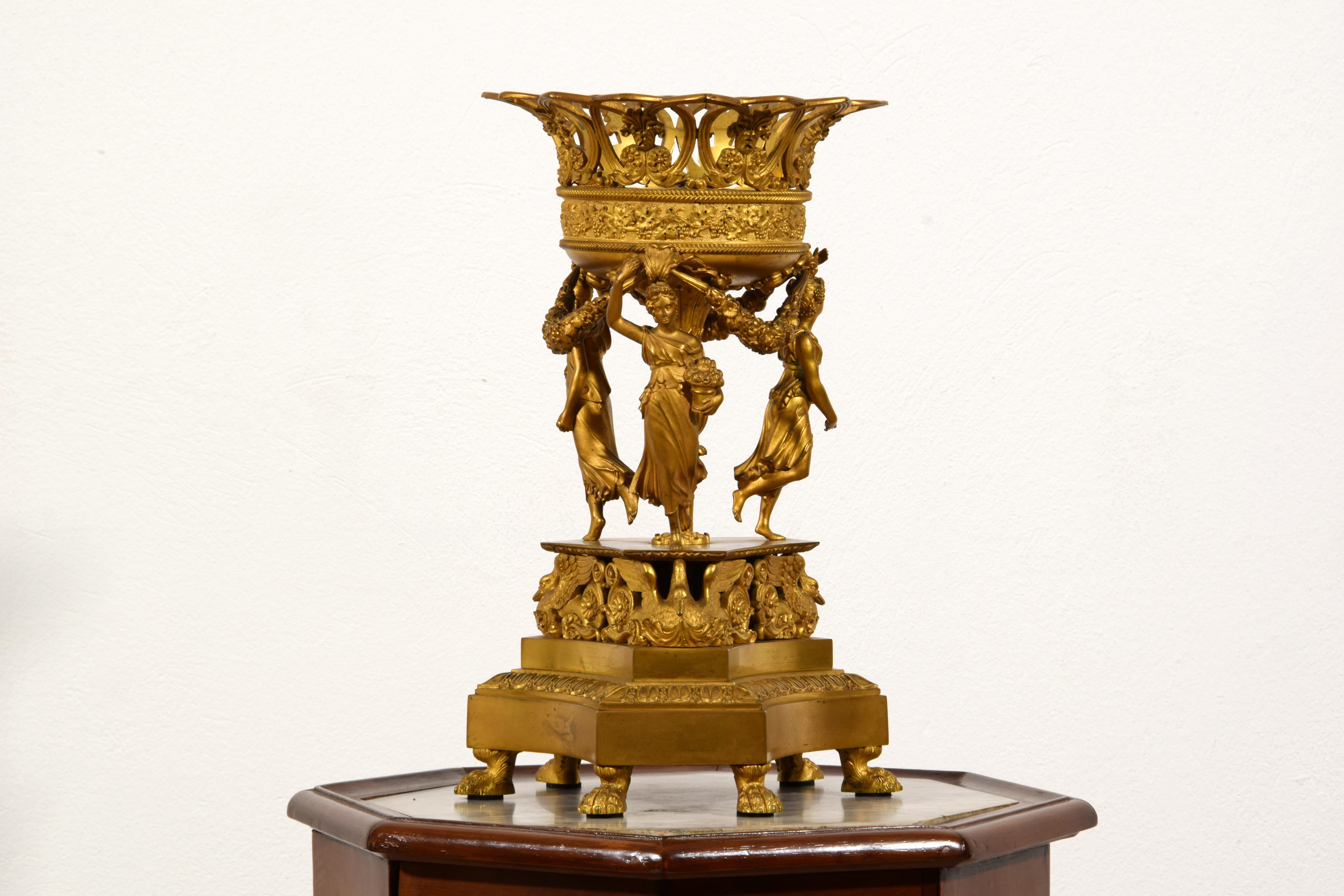 Centrotavola in bronzo dorato Impero francese del XIX secolo
Questo raffinato centrotavola è stato realizzato in Francia all'inizio del XIX secolo, durante il periodo dell'Impero, in bronzo finemente cesellato e dorato.
La base, con sei piedi in