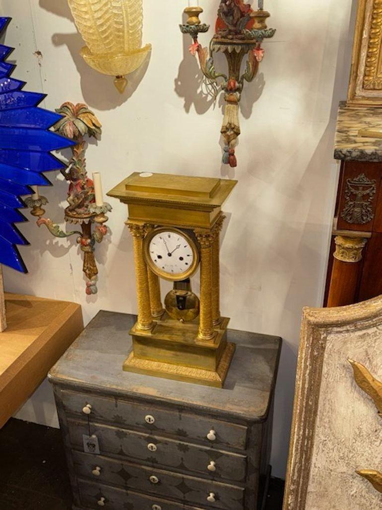 This 19th Century French Empire Mantle Clock features a stunning frame made of gilt bronze, exuding elegance and luxury typical of the Empire style. The clock showcases intricate detailing and craftsmanship, with a rich bronze finish adding