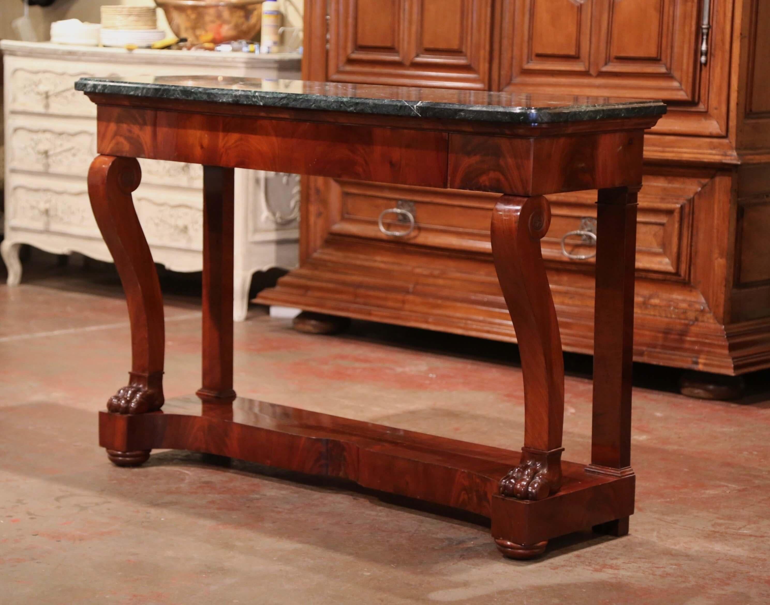 This elegant antique console was crafted in France, circa 1880. Standing on scrolled front legs ending in paw feet, and pilaster legs in the rear over a stretcher platform bottom shelf, the table features a large drawer across the front; the surface