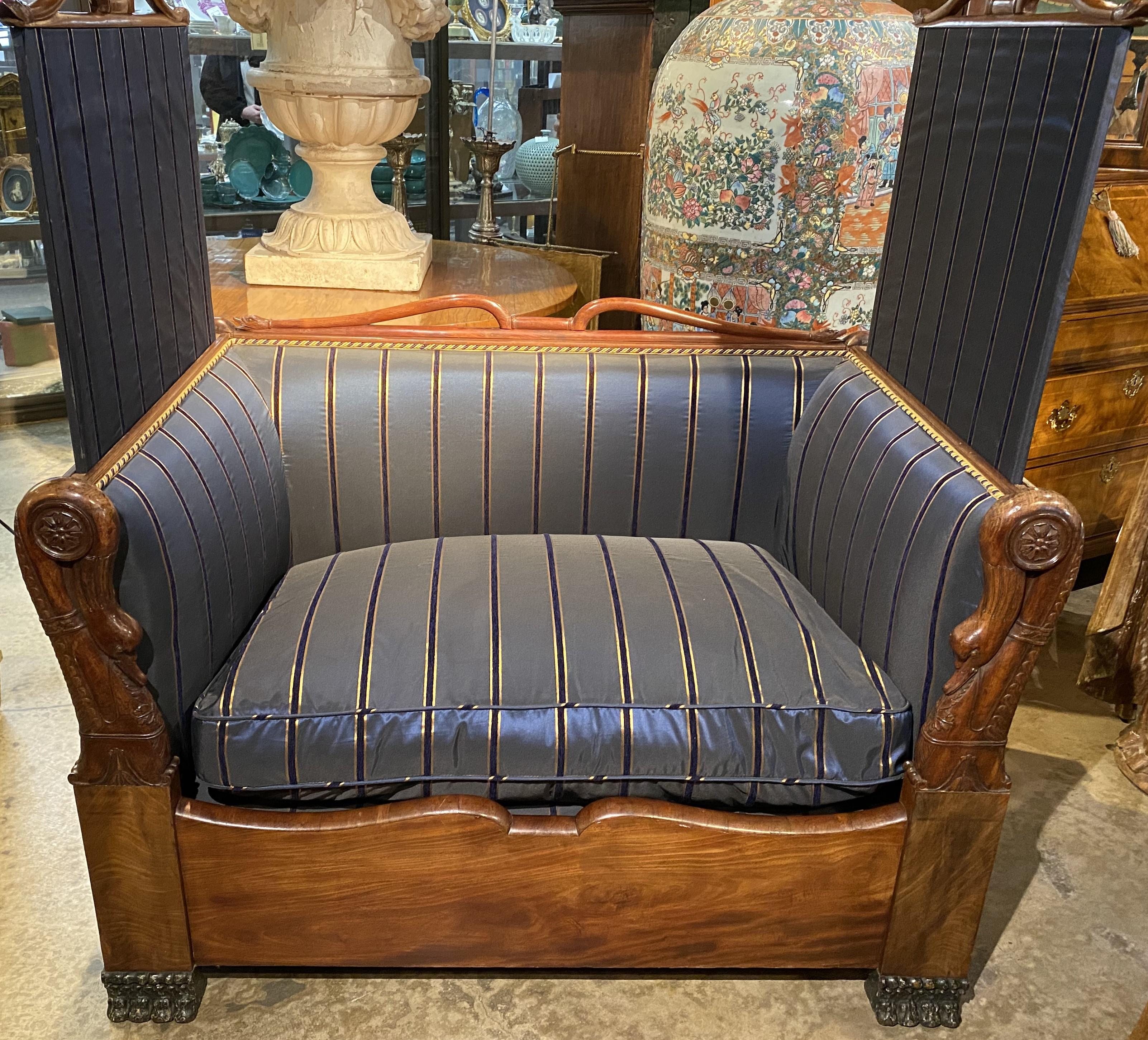 A wonderful French Empire walnut “kissing settee” with carved swan arms, crests, and corners, privacy screens which raise up on each side, adorned with striped satin upholstery and seat cushion with gold & purple cord accents, all supported by