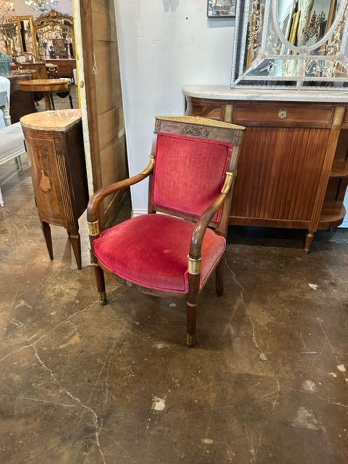 Charmant fauteuil Empire français du XIXe siècle en acajou et en vermeil. Tapissé d'un tissu velours rouge. Une déclaration élégante !