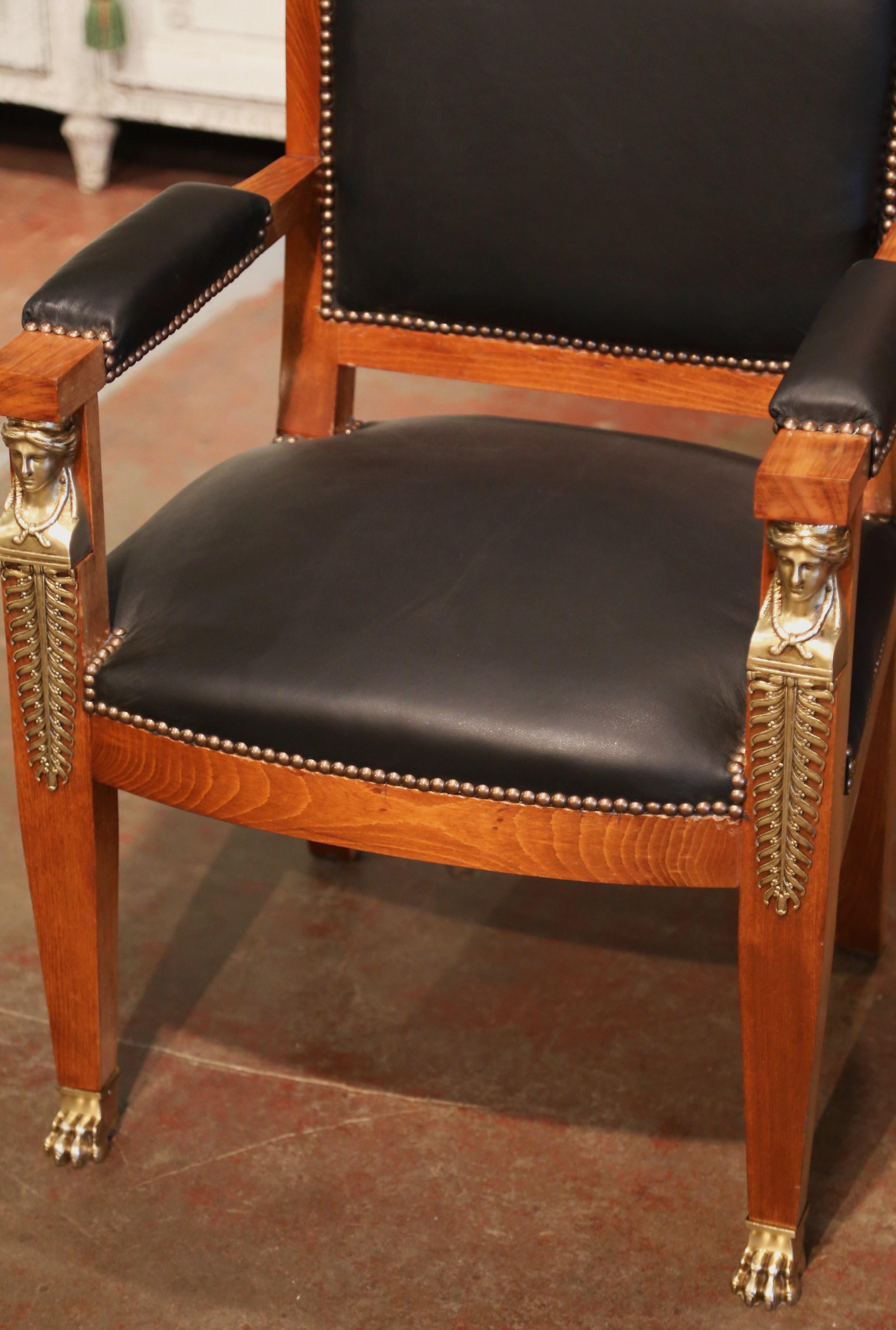 Decorate a man's office or study with this elegant antique armchair. Hand carved in France circa 1890 and built of mahogany, the armchair stands on tapered legs decorated with gilt bronze female figure mounts at the shoulder, and ending with paw
