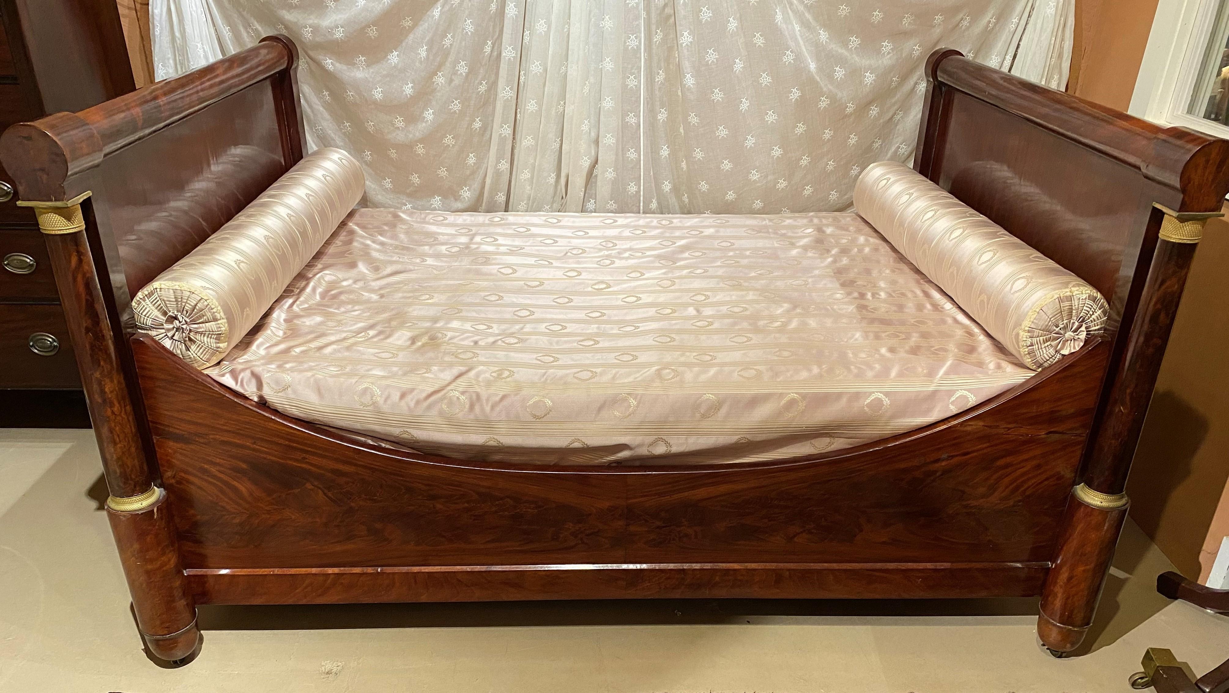 A fine Empire mahogany bed, also referred to as an alcove bed or daybed, with full corner front columns with ormolu capitals, metal casters, and nicely appointed with a sheer white canopy embroidered with lyre decoration and accented with clear edge