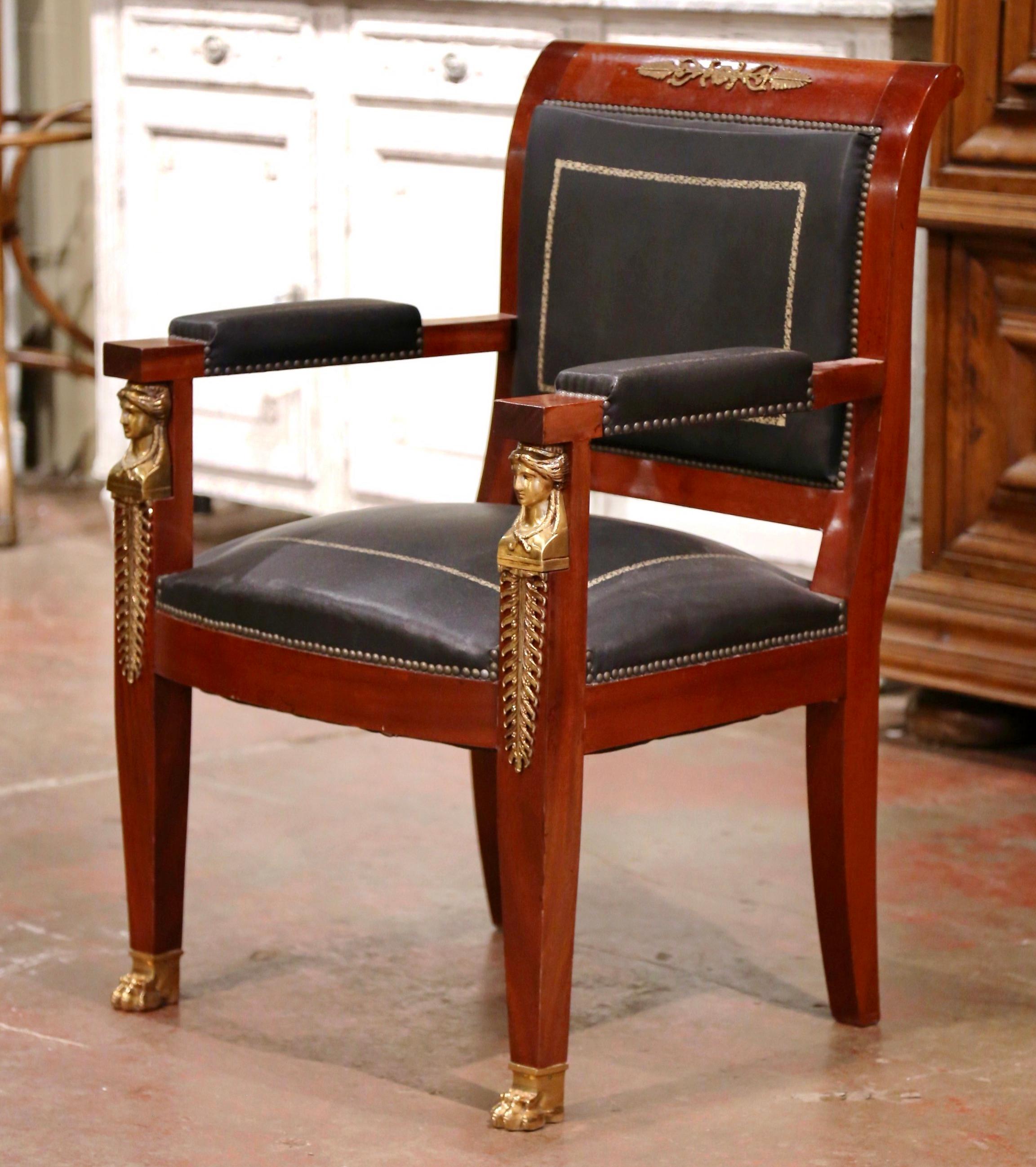 Decorate a man's office or study with this elegant antique armchair. Hand carved in France circa 1890 and built of mahogany, the armchair stands on tapered legs decorated with gilt bronze female figures mounts at the shoulder, and ending with paw