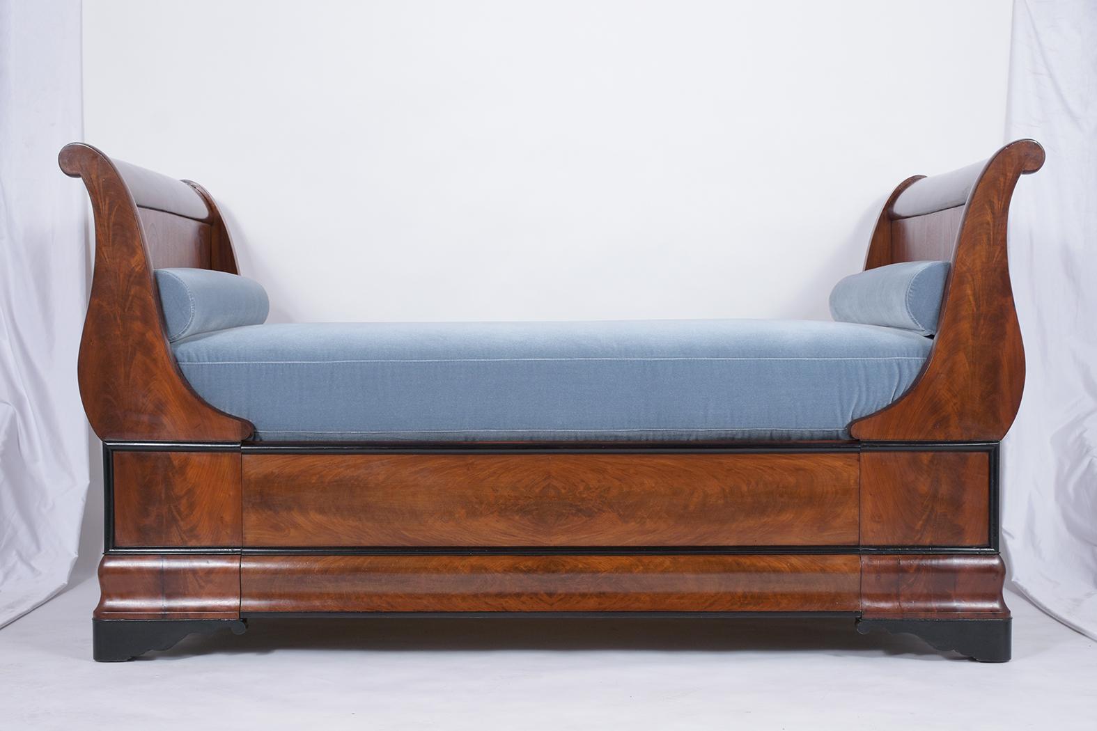This circa 1830s French Empire daybed has been professionally restored, is crafted out of mahogany wood, and features a solid frame finished in its original rich mahogany finish with ebonized molding details along the edges. This daybed comes with a