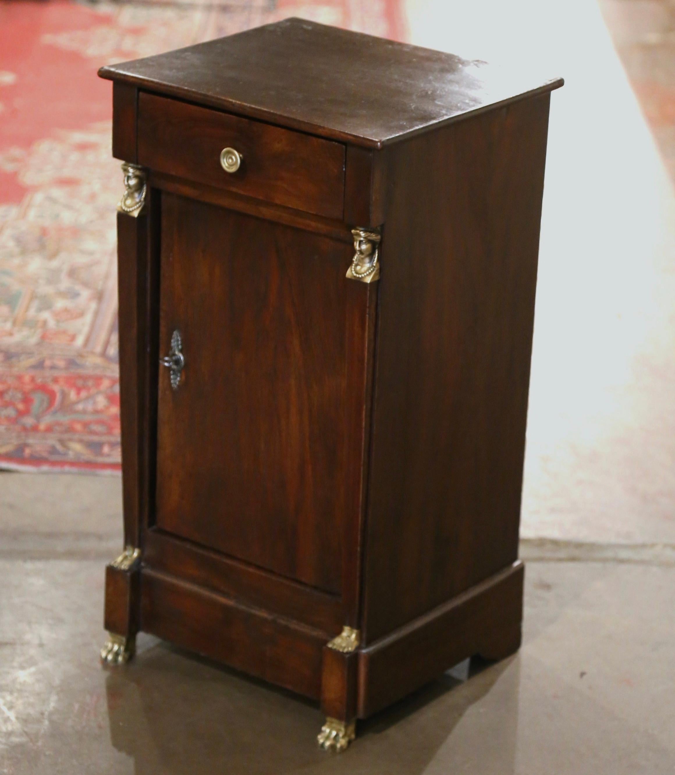 Crafted in France, circa 1880, the elegant antique cabinet stands on bronze paw feet over a wide straight bottom plinth; it is decorated at the shoulder with Egyptian woman faces, ending with feet sculptures at the bottom. The small fruit wood chest