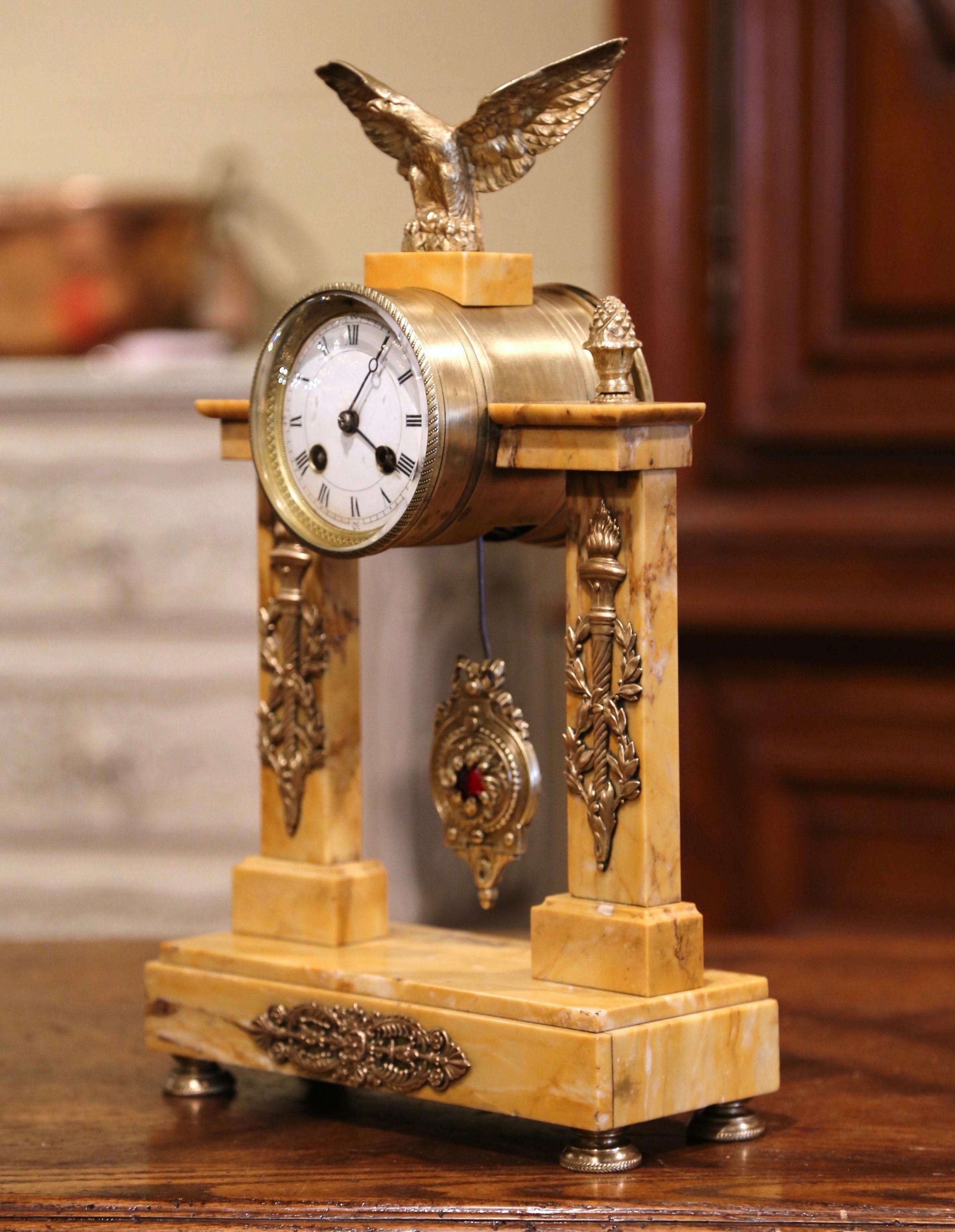 Decorate a mantel or an office with this elegant portico marble and bronze antique clock. Crafted in Paris, France circa 1860, the time keeper stands on small round feet over a rectangular marble base; it features dual columns decorated with flaming