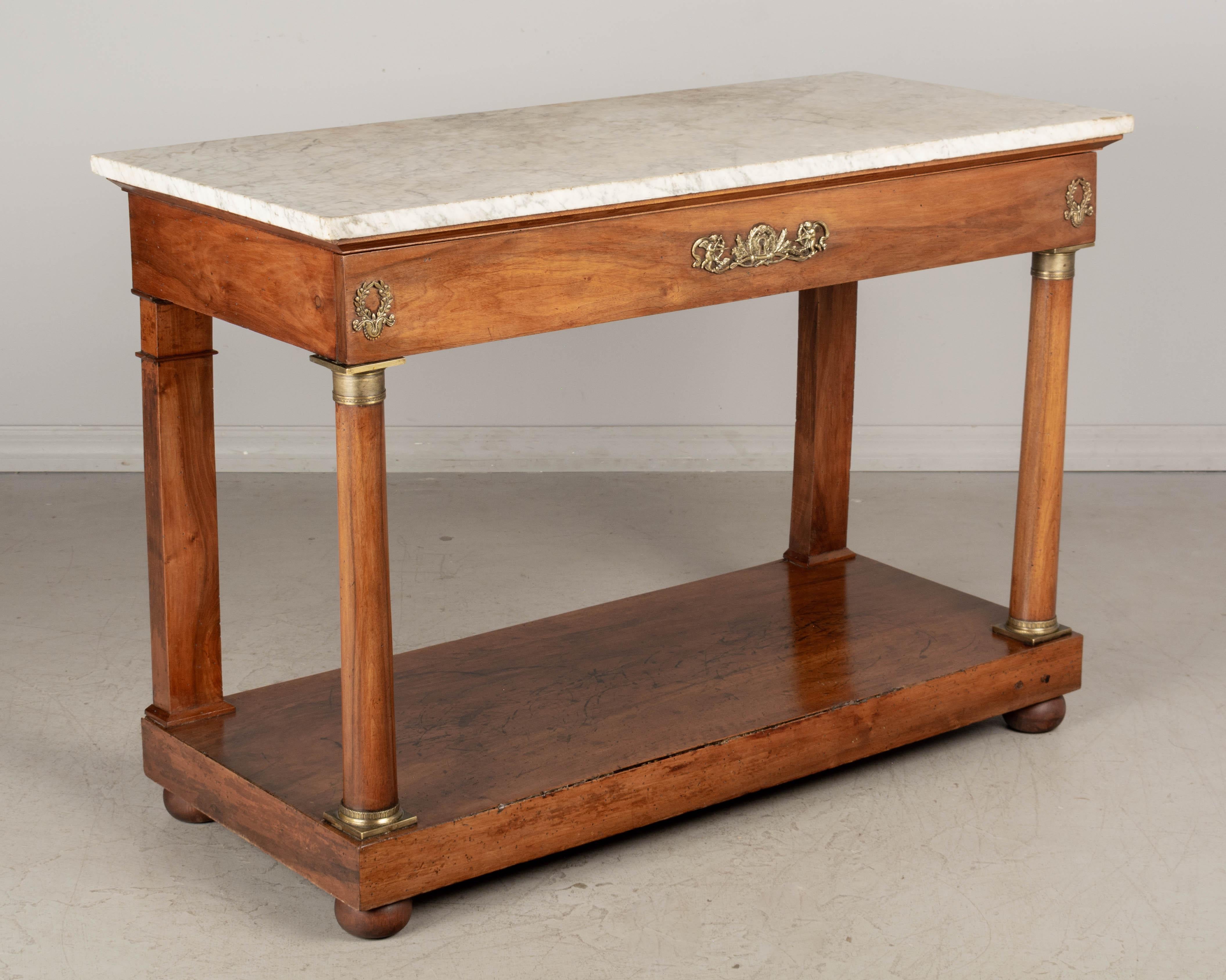 An early 19th century French Empire marble-top console table made of solid walnut. Large drawer with original fine cast bronze decoration. Bronze mounted turned column supports in front. Dovetailed construction. Pine as a secondary wood. New bun