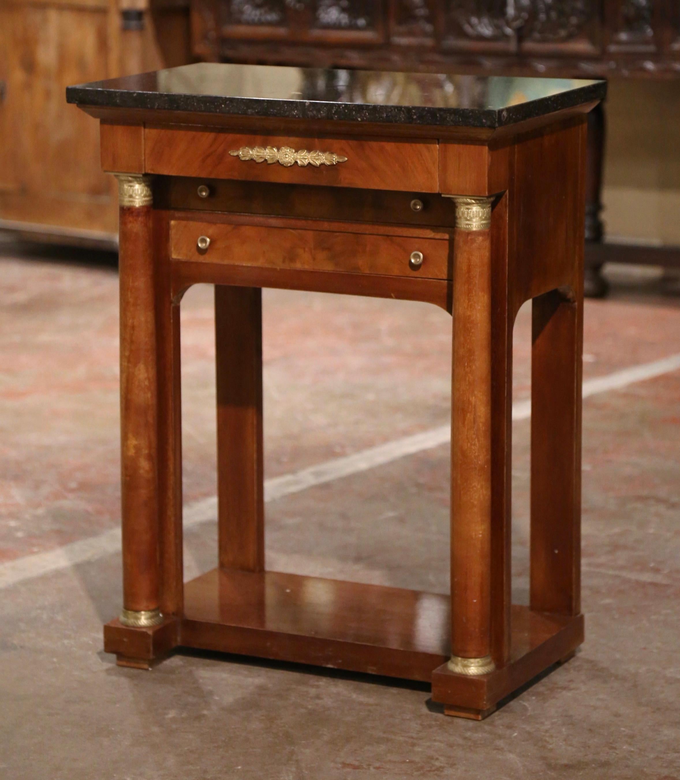 Crafted in France, circa 1850, the elegant antique cabinet stands on front rounded columns ending with bun feet and embellished with decorative brass mounts at the shoulder and the base. The small chest features three drawers across the front