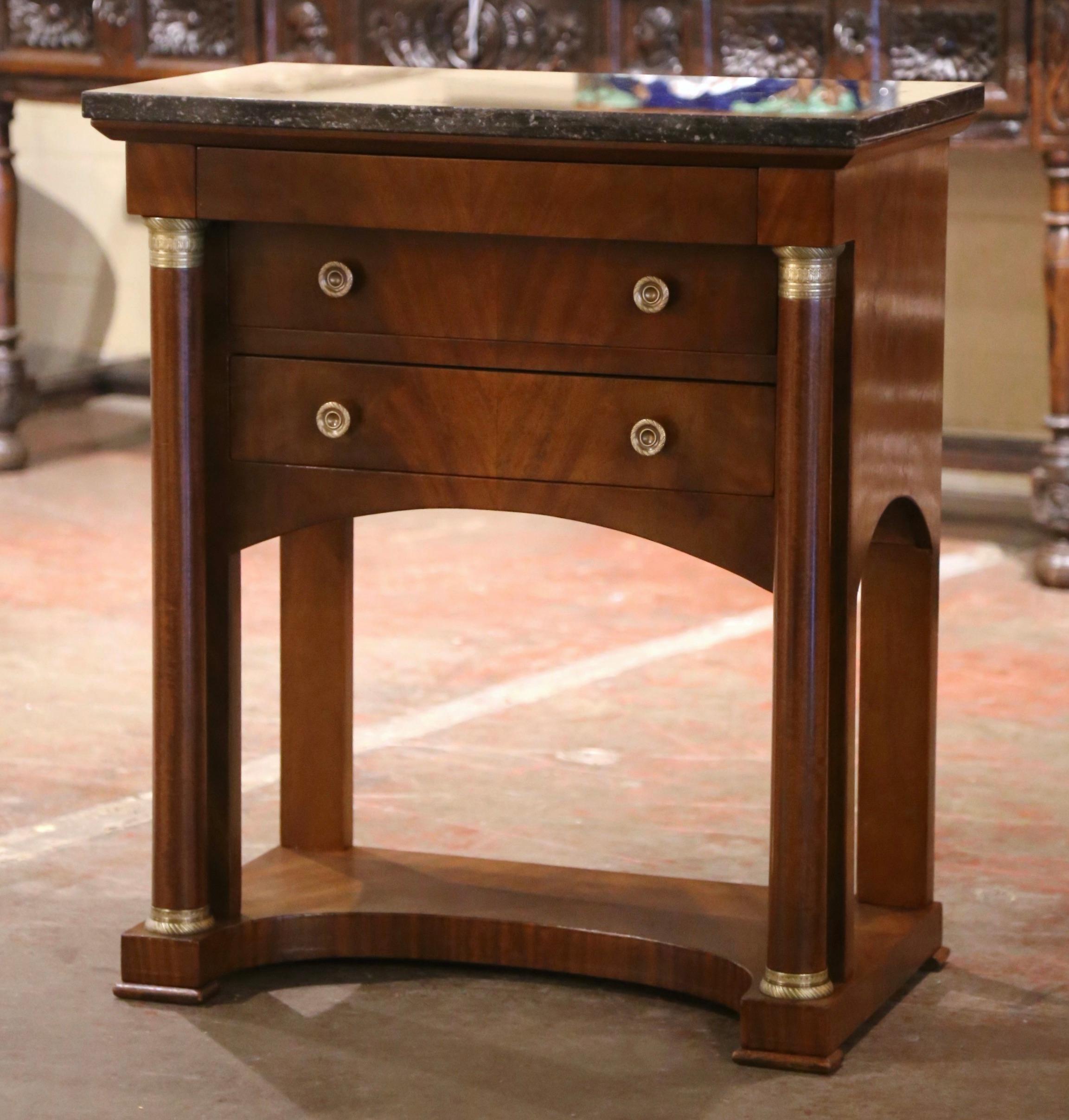 Crafted in France circa 1870 and built of mahogany wood, the elegant antique cabinet stands on front rounded columnar supports embellished with decorative bronze mounted rings at the shoulder and the bottom, and ending with square feet. The small