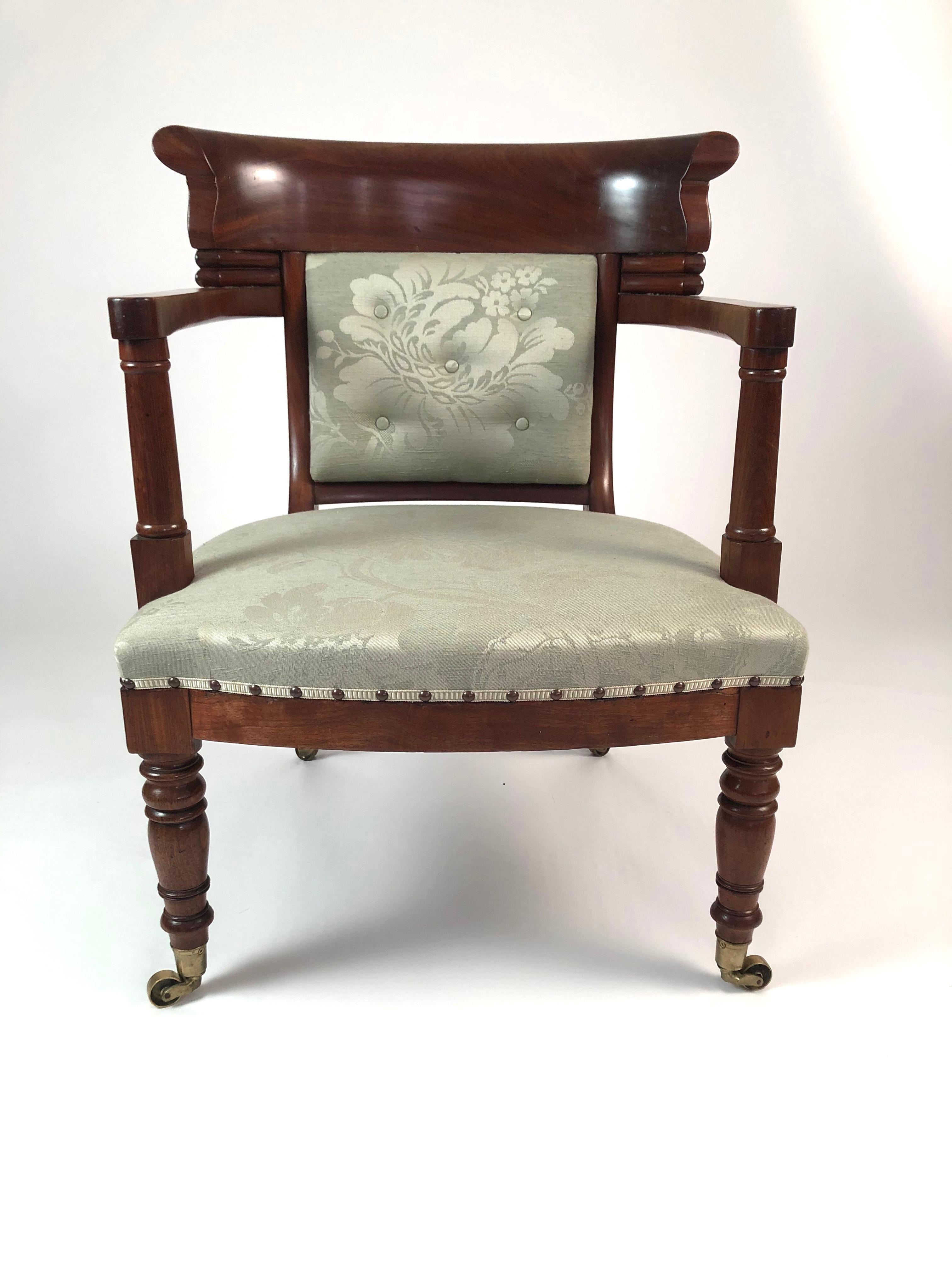 A generously proportioned 19th century French Empire period fauteuil in mahogany, the curved tablet back with bold channel carving supported by curved arms over columnar supports, over a high quality celadon green damask upholstered seat supported