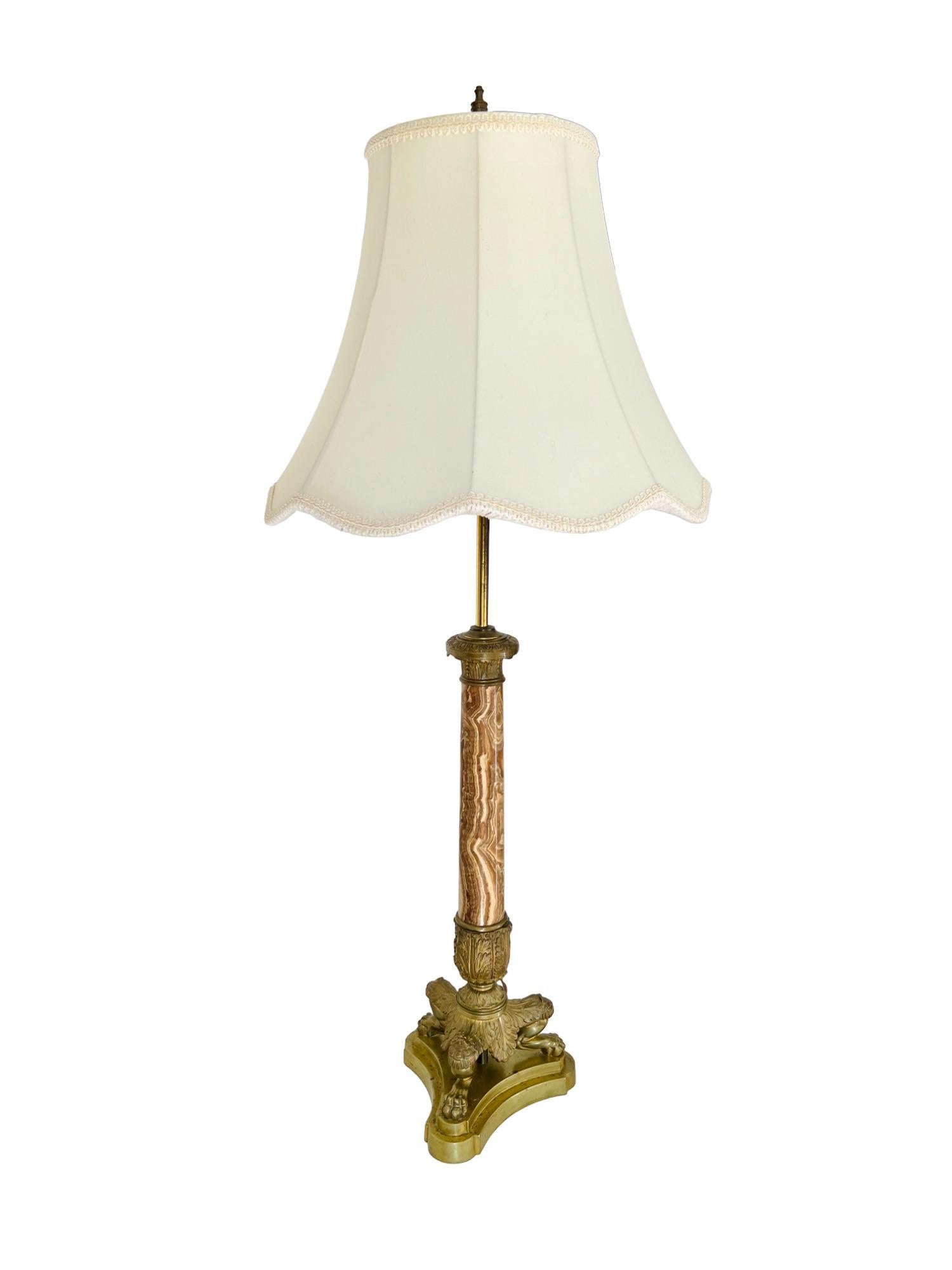 A 19th century French Empire (converted) two-light table lamp with shade. Neoclassical design featuring a tapered onyx shaft ornamented with decorative brass mounts supported by a triform lion paw footed base. Two light sockets with individual pull