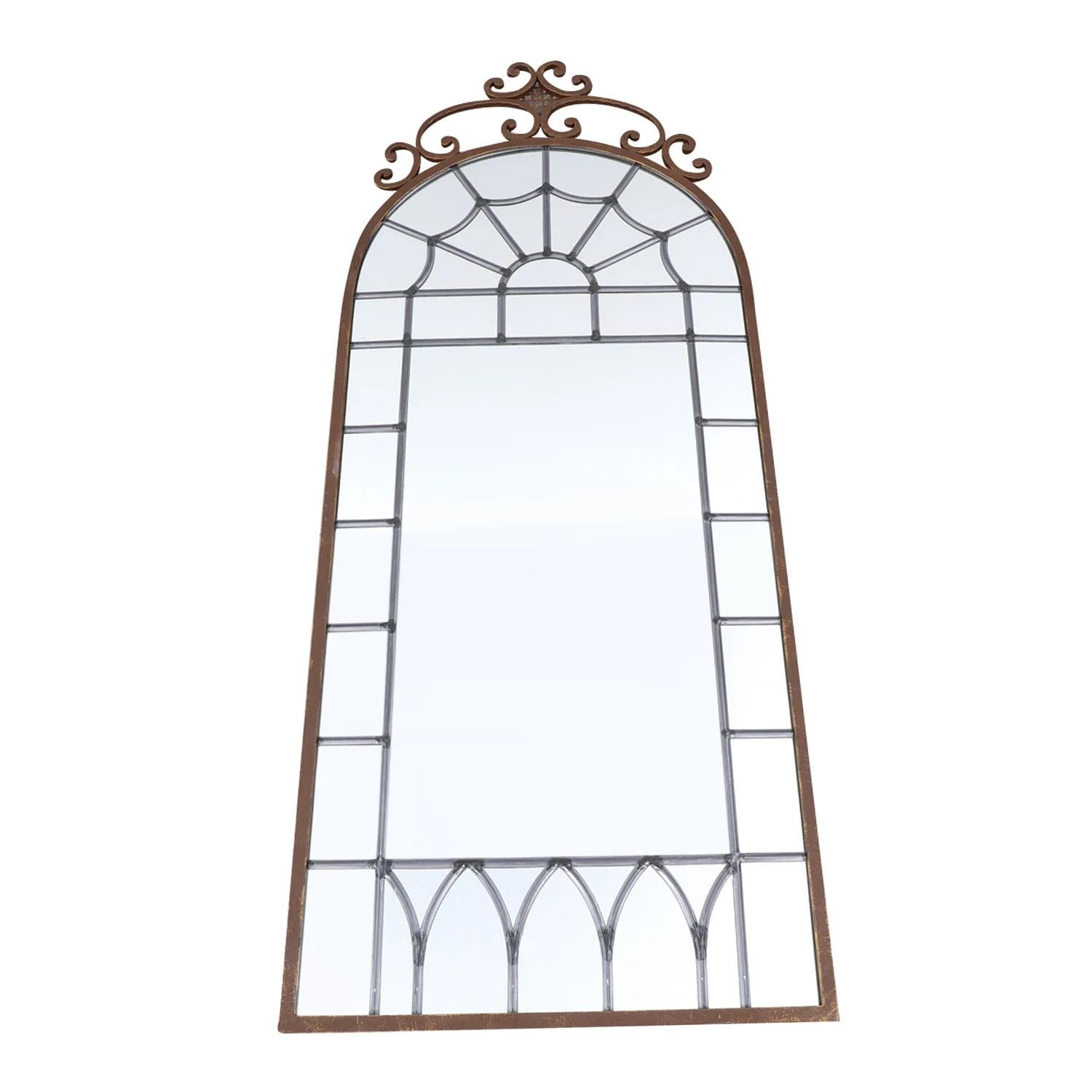 An antique French pair of wall mirrors with an arched top, made of hand crafted metal in good condition. The large mirror is consisting its original mirrored, leaded glass particularized by detailed flower crafting. The Parisian décor pieces