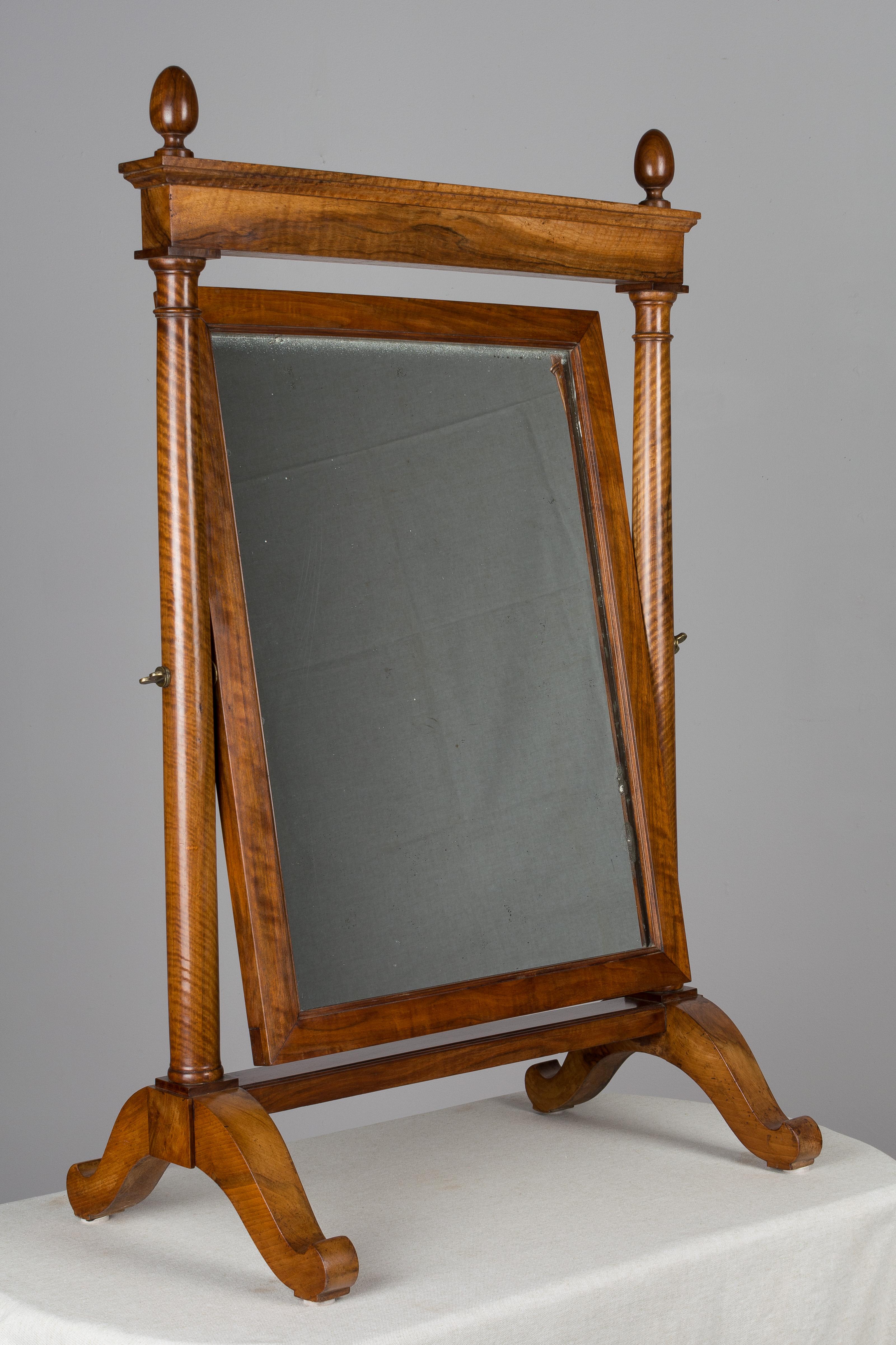 miroir de style Empire français du 19ème siècle, en noyer massif, avec un beau grain de bois et une patine cirée. De belles proportions et une grande échelle pour un miroir de table. Finitions en forme d'œuf tourné, miroir épais avec quelques