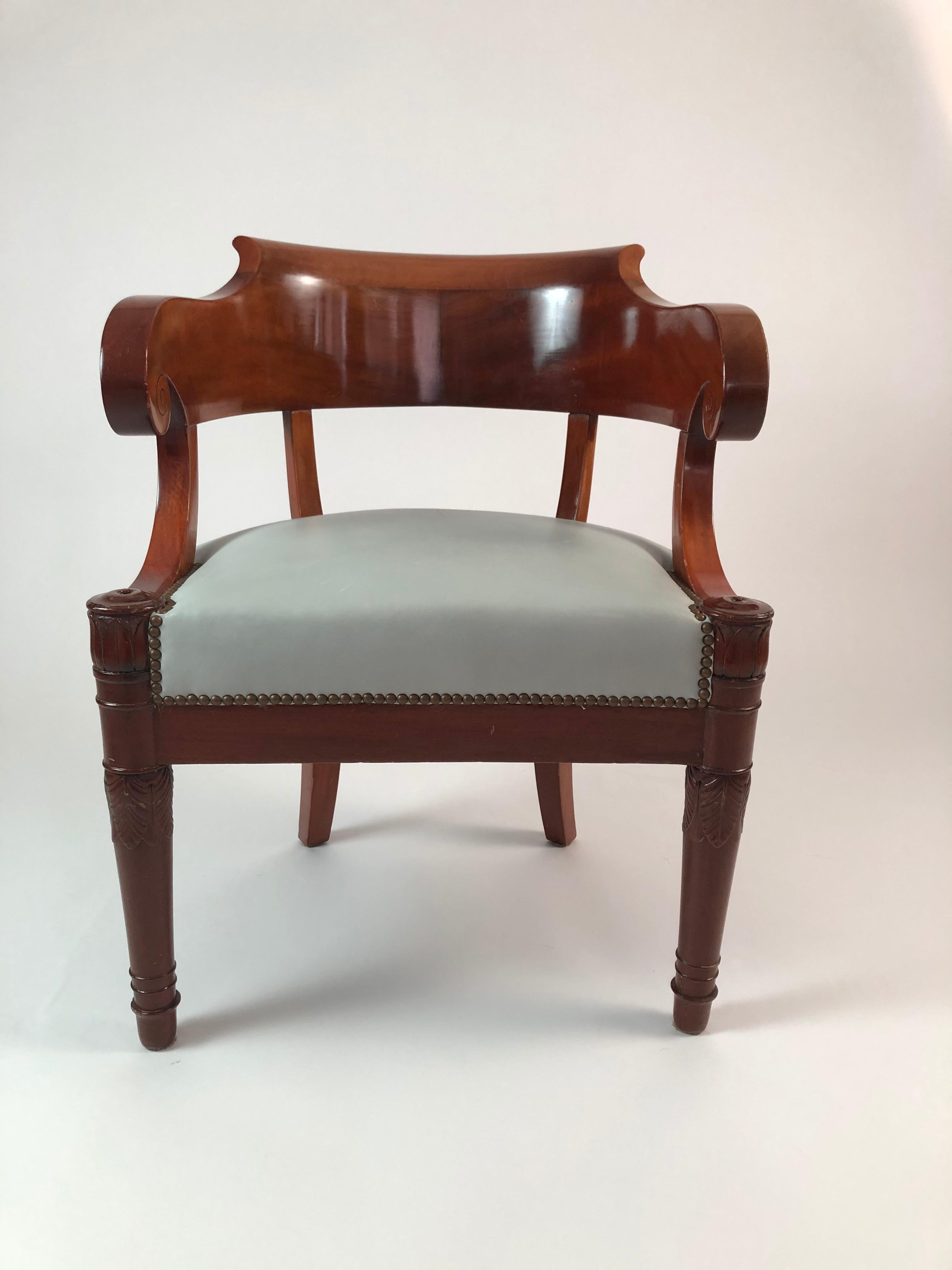 A fine quality early 19th century French Empire period fauteuil in mahogany, the curved backrest terminating in carved scrolled armrests over the seat upholstered in celadon green upholstery, the front tapering legs topped by roundels over lotus and