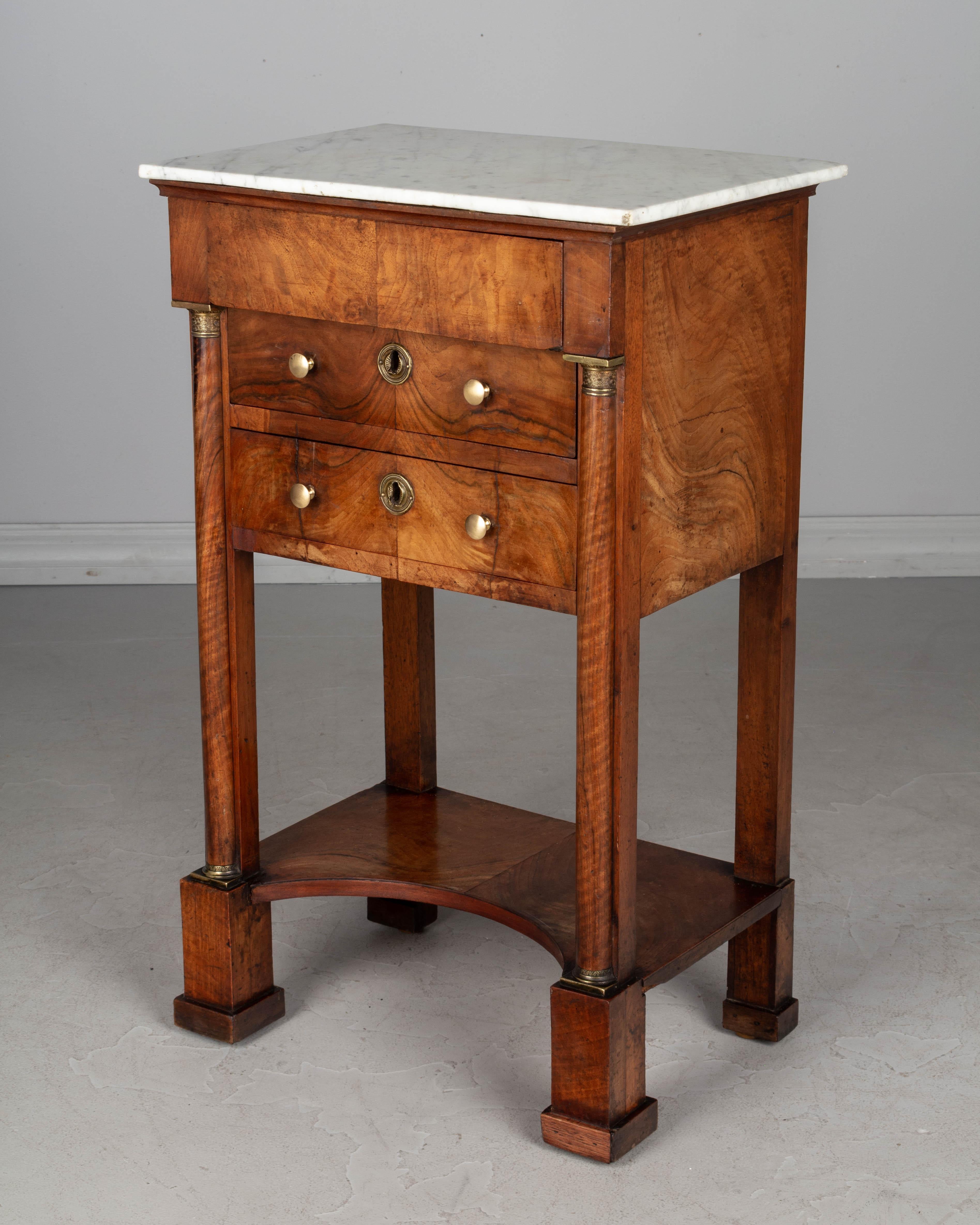 A fine 19th century French Empire period side table or nightstand made of solid walnut and veneer of walnut and finished on all four sides. Book matched veneers with beautiful swirling patterned wood grain. Two dovetailed drawers with original