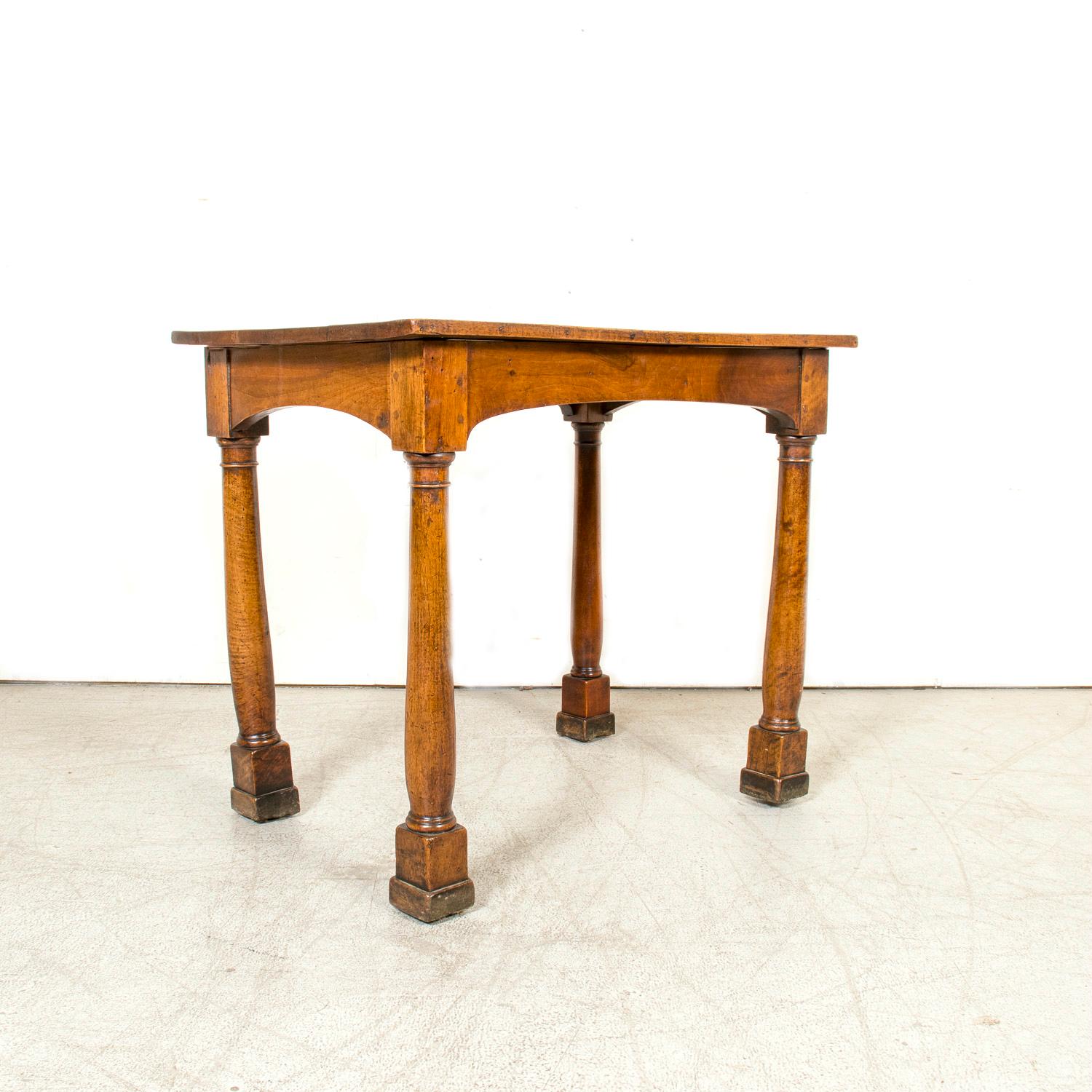 Cette exquise table d'appoint d'époque Empire français est un superbe exemple de l'artisanat du début du XIXe siècle. Fabriqué à la main en noyer par des artisans qualifiés près de Lyon, vers 1810, il présente un plateau rectangulaire avec un grain
