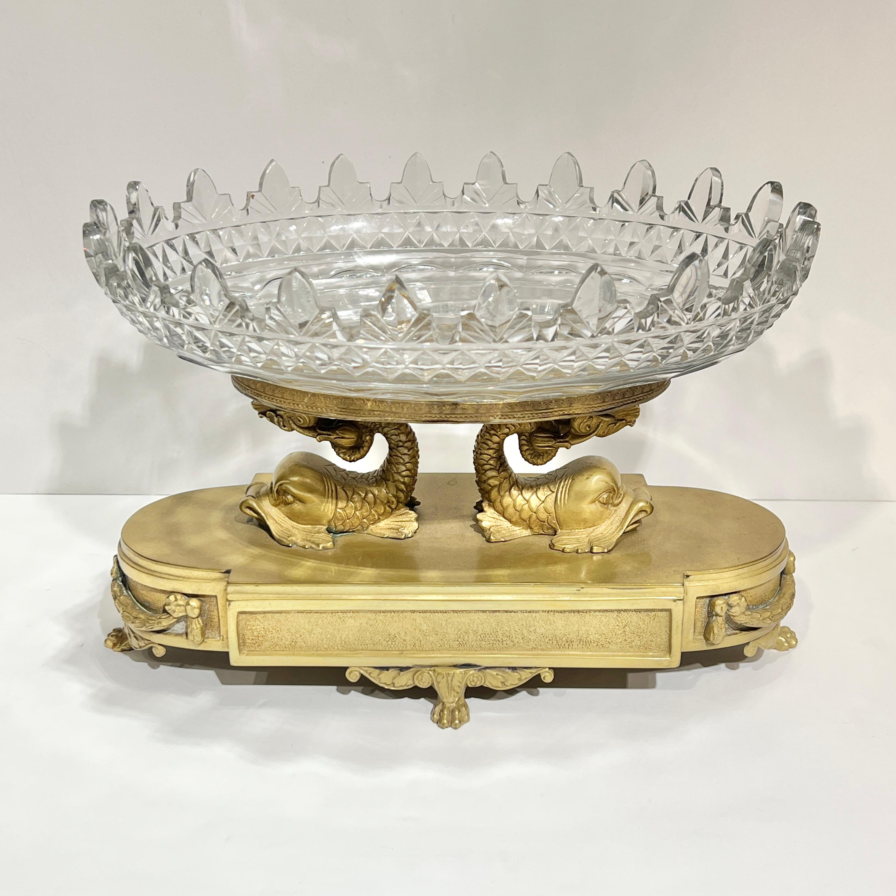 Centrotavola in bronzo dorato del XIX secolo in stile Impero francese con coppa ovale in vetro tagliato sostenuta da due delfini stilizzati su una base ovale sollevata da zampe di leone.  13 1/4 pollici di larghezza, 8 5/8 di altezza e 9 di
