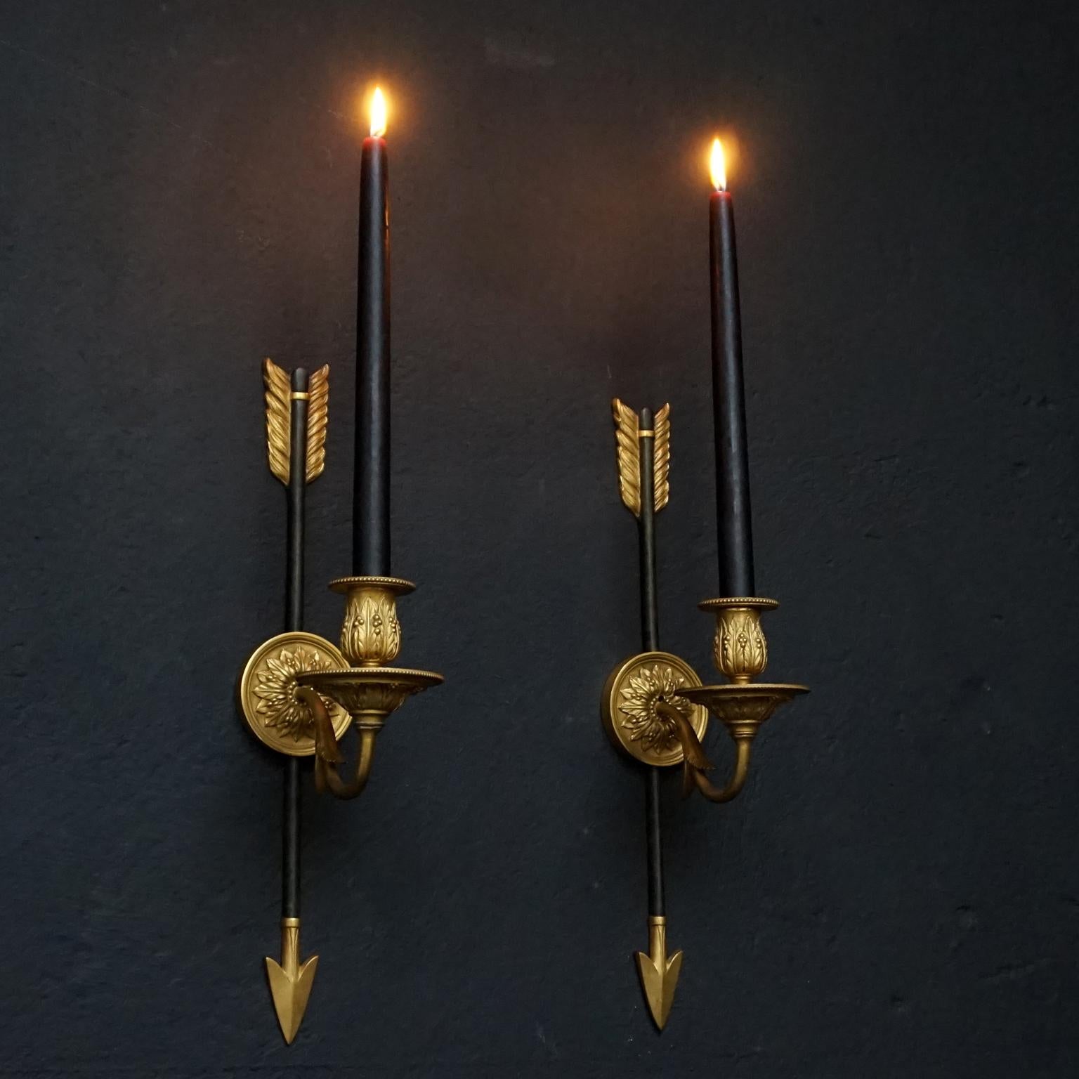 Antique pair of French First Empire doré bronze wall candlesticks in arrow form.
Decorated with palmette or palm leaf decor. 

These sconces have not been electrified but they have holes so they could easily be modified.

This set comes with a
