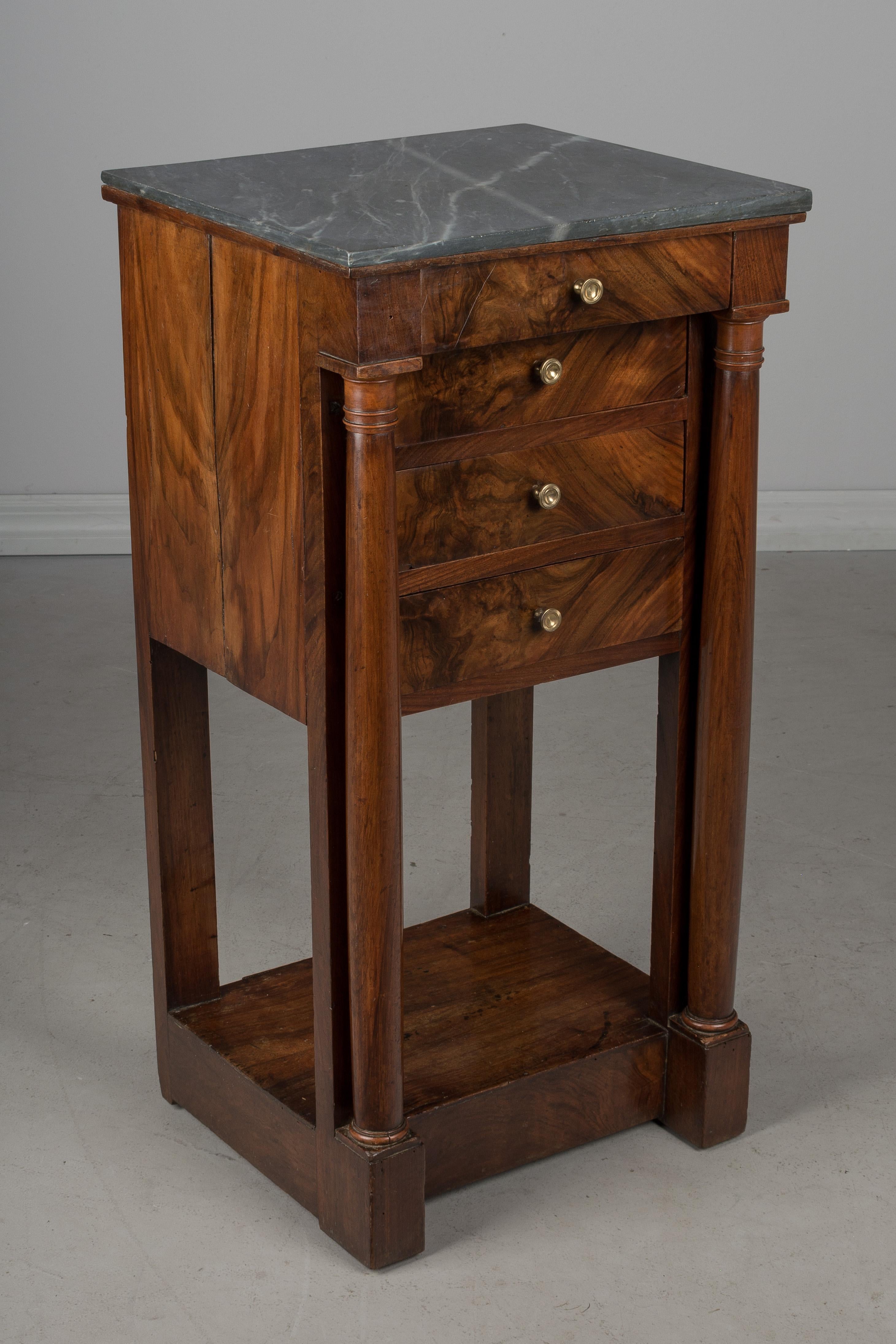 A fine 19th century French Empire marble-top chevet, or side table made of solid walnut with crotch walnut veneer and pine as a secondary wood. Four dovetailed drawers with replaced brass pulls. Turned wood columns in the front. Exceptional