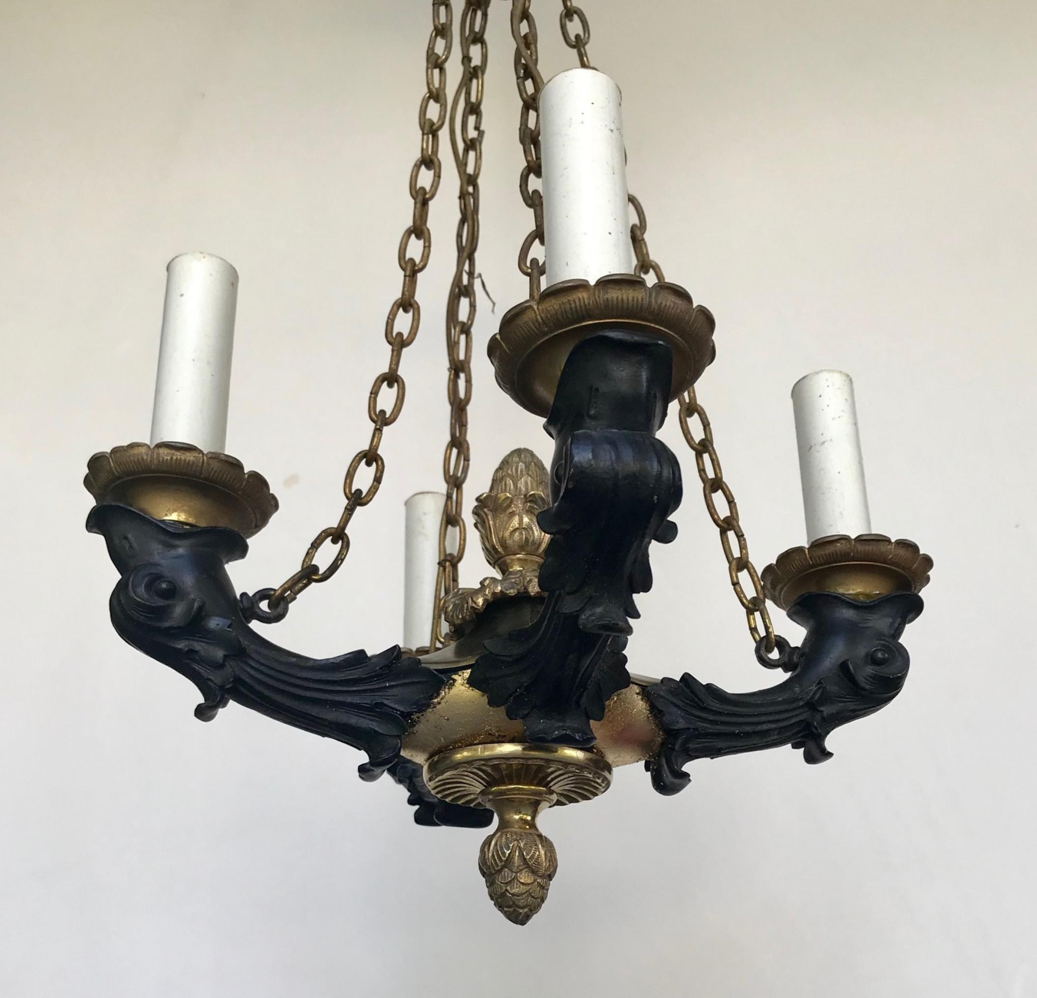 19th century French empire small patinated bronze chandelier.

Classic French Empire small bronze four light chandelier. It has rich ormolu finials and ornamentation. Four patinated bronze dolphin heads hold the candle cups. Condition is good with