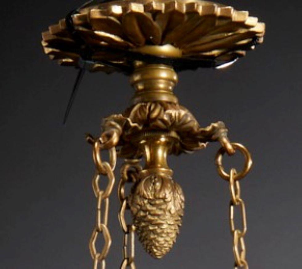 19th century French Empire style 3-arm fixture with flame finial, unmarked, not electrified. A charming light fixture, this chandelier will add a lovely candlelit ambiance to any setting. 

Three chains hang from a central medallion detailed with