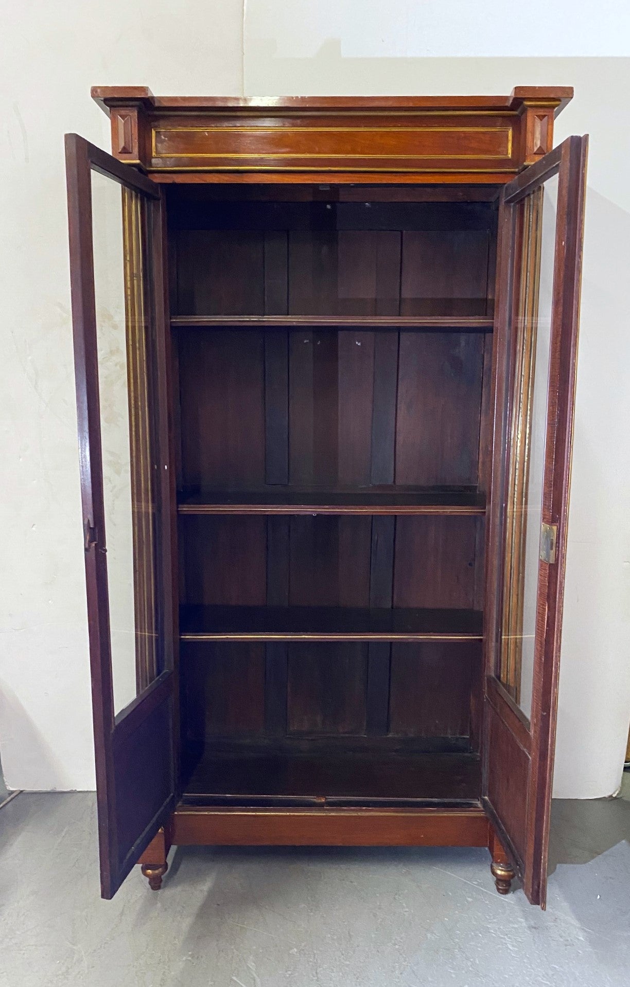 Empire-style cabinet/bookcase. Two glass doors with collum on each side adjustable and shelves with. The cabinet has gold finish brass accents and an original key.